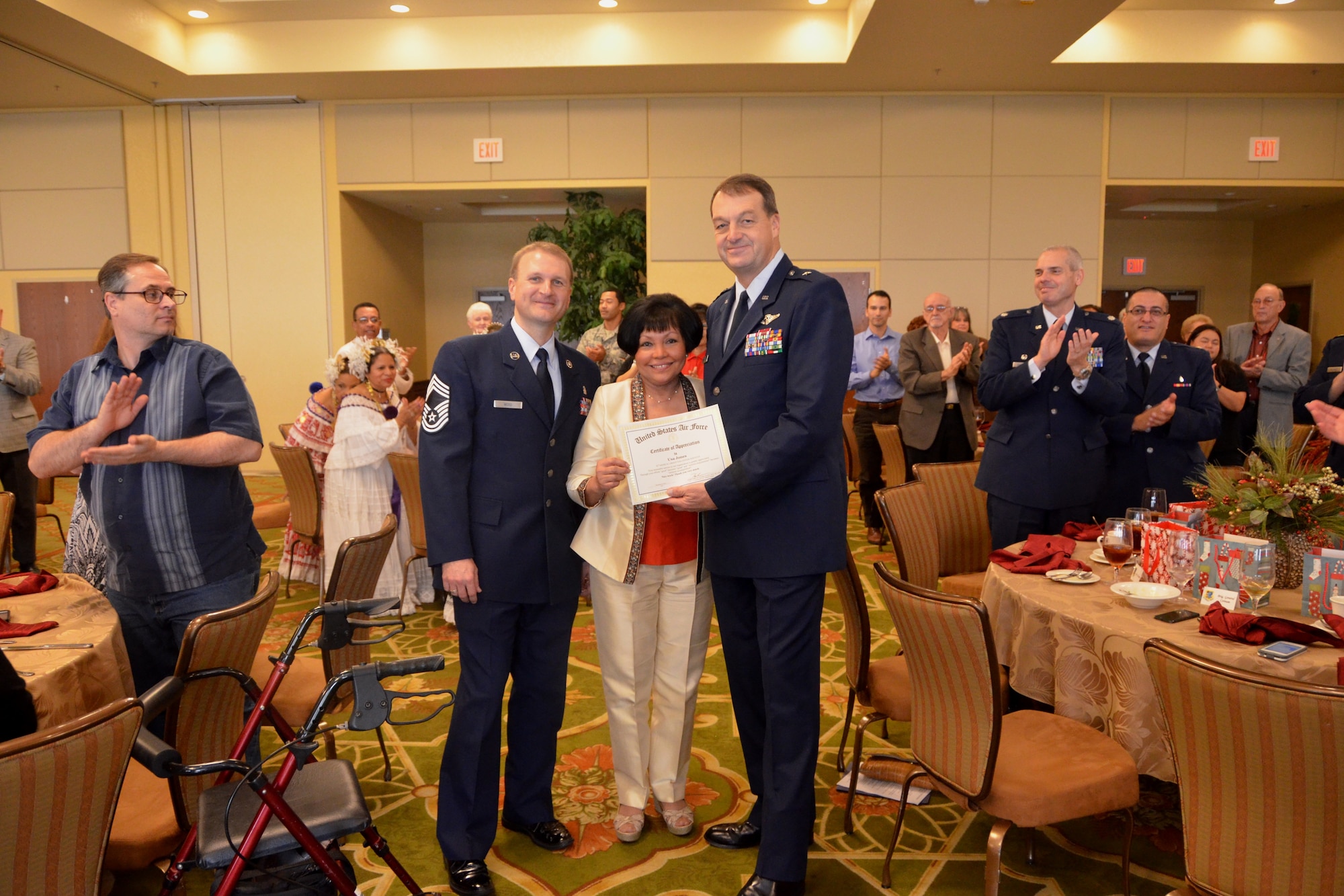Brig. Gen. (Dr.) Kory Cornum, 81st Medical Group commander, right, and group superintendent Chief Master Sgt. Michael Woods present volunteer coordinator Usa Jones a certificate recognizing her 32 years of volunteer service with Keesler Medical Center Dec. 6, 2013,.  She was one of 52 people honored during the annual awards luncheon.