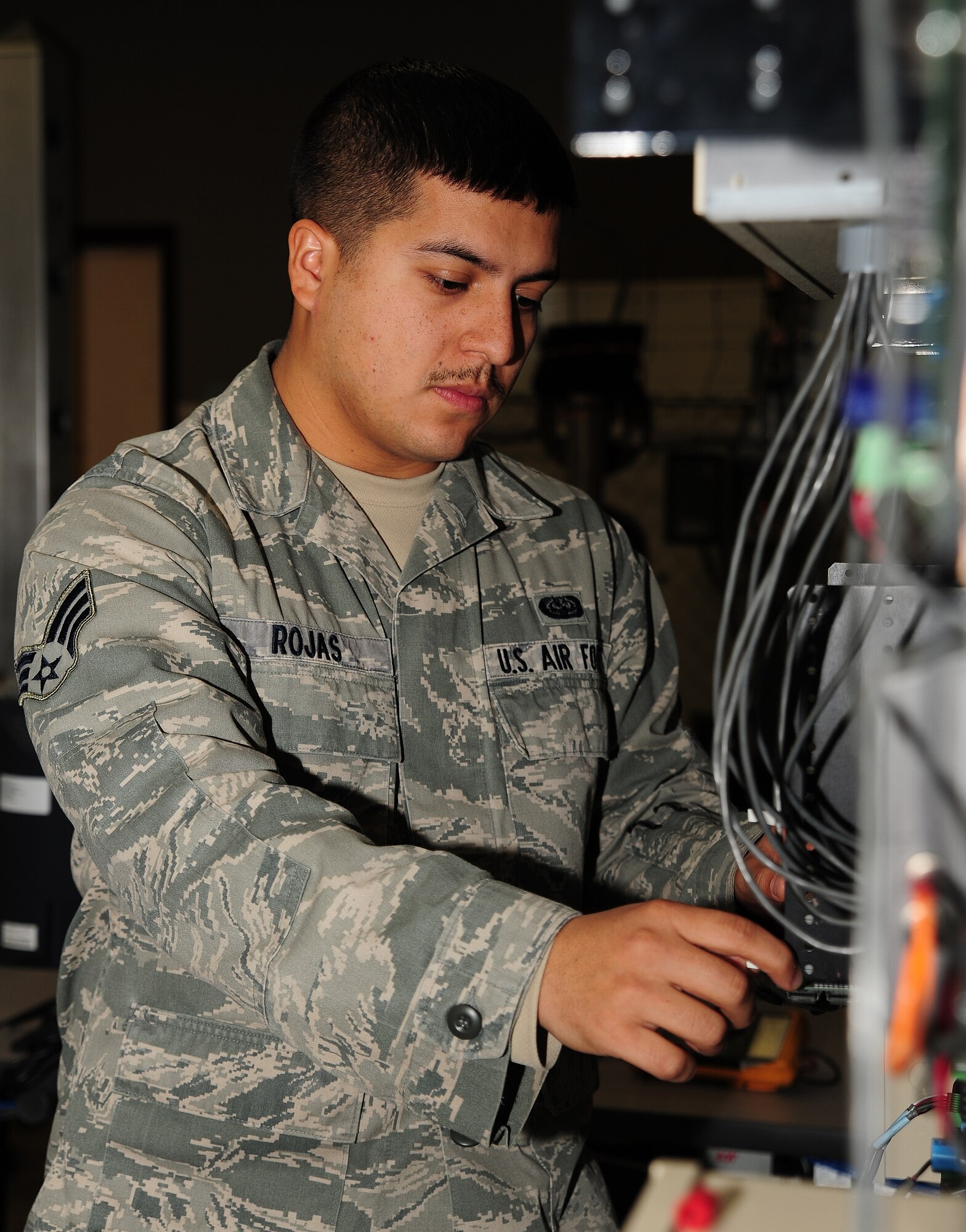 Senior Airman Luis Rojas, 509th Communications Squadron intrusion detection systems technician, inspects an alarm for deficiencies at Whiteman Air Force Base, Mo., Dec. 5, 2013. To ensure the device functions properly, Rojas looked for corrosion and ensured electrical currents were displaying the correct measurement. (U.S. Air Force photo by Staff Sgt. Nick Wilson/Released)