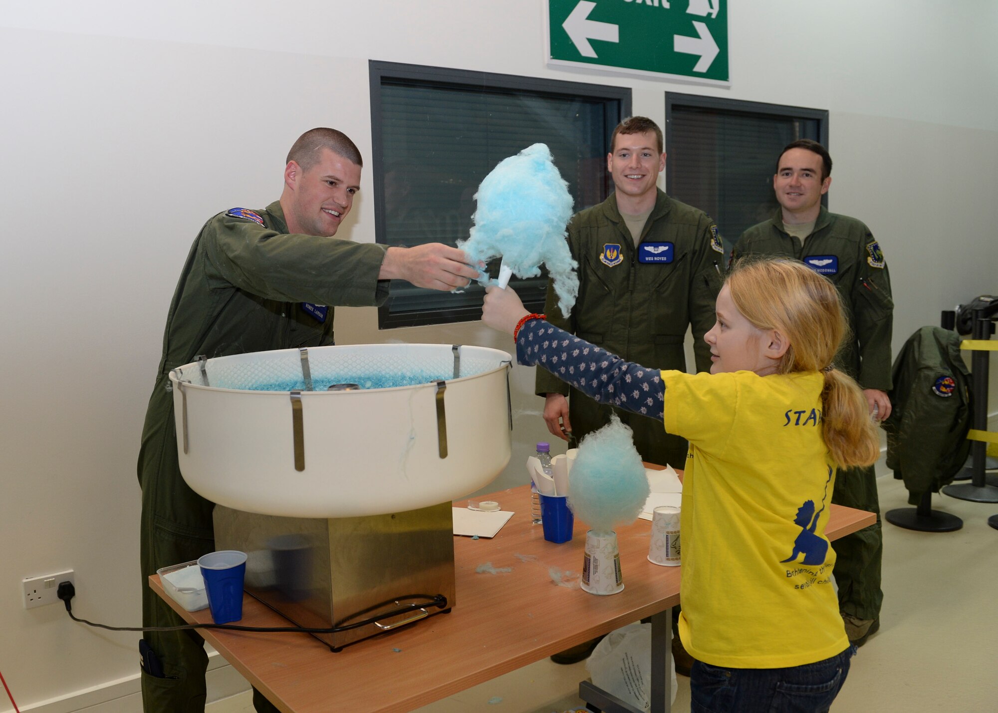 Capt. Matthew Larson, 492nd weapons systems officer, hands homemade cotton candy Logan Machin, 10, during the Duxford Christmas party at the Imperial War Museum, Dec. 14, 2013. Established during World War II, the Duxford Christmas party was created by the Royal Air Force Duxford 78th Fighter Group to supply gifts and support to children from the London area who were orphaned by the war. (U.S Air Force photo by Airman 1st Class Nigel Sandridge/ Released)