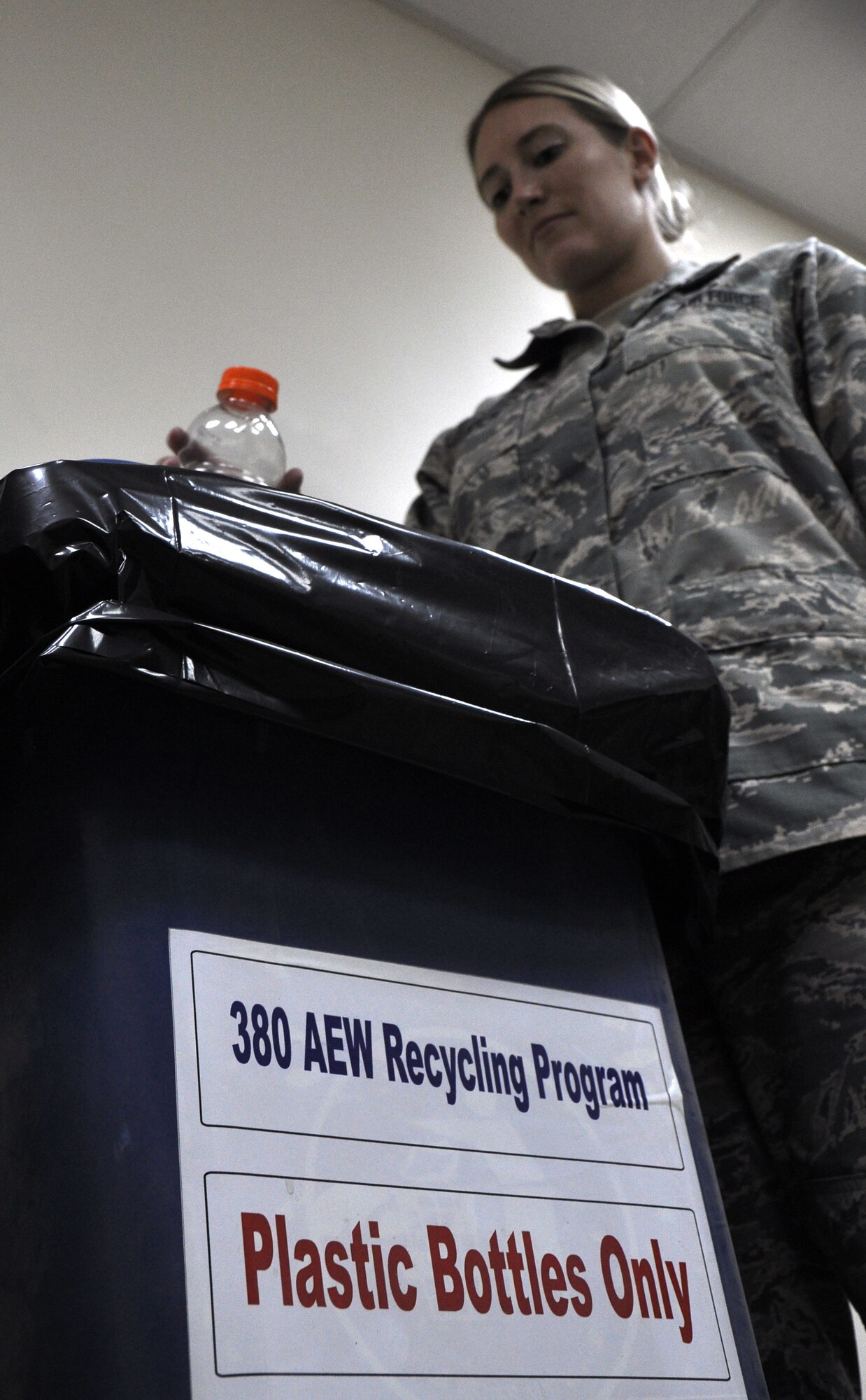 An Airman tosses a bottle into one of the many recycling bins located around the base. The 380th Air Expeditionary Wing's recycling program recycles plastic bottles, aluminum cans, shredded white paper, and flattened cardboard boxes, in addition to many other items. (U.S. Air Force photo by Master Sgt. April Lapetoda/Released)