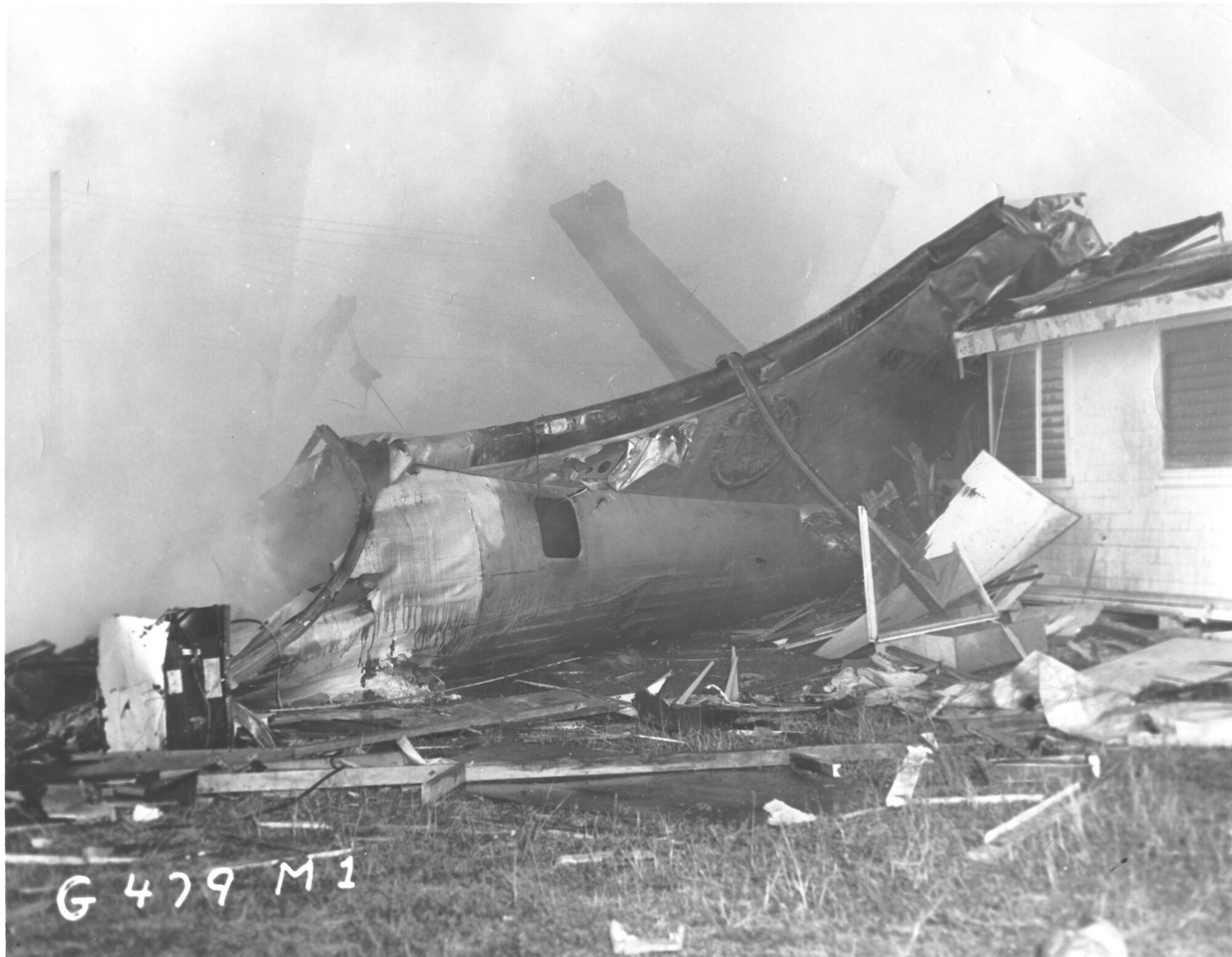 A damaged B-29 tail section leans against Capt. Bartley’s home after crashing on Andersen Air Force Base, Guam, Dec. 17, 1953.  The open ditching hatch is where 1st Lt. Jack Patton, radar officer, Airman 1st Class Bill Backman, tail gunner, and  Airman 2nd Class Bob Jensen, electronic counter-measure operator, escaped. (U.S. Air Force photo/Released)