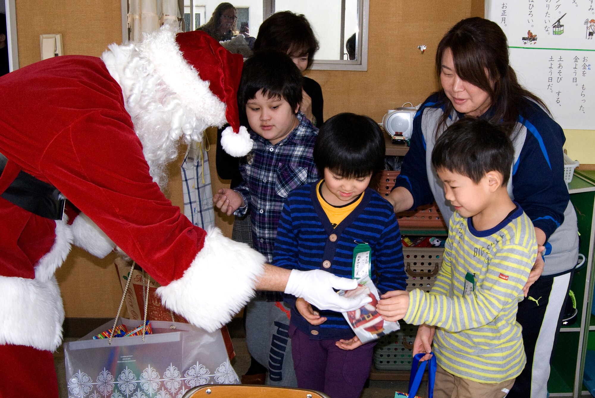 Santa Claus hands a small gift bag of candy canes and treats to a student during a 
visit to Kamikubo Shougaltuko Elementary School in Misawa City, Japan,  Dec. 16, 
2013. Members of the Misawa community spread Christmas cheer as they handed 
out small gift bags of candy along with stickers to students and school staff in an 
effort to expand relationships between the American and Japanese communities. 
(Courtesy Photo)
