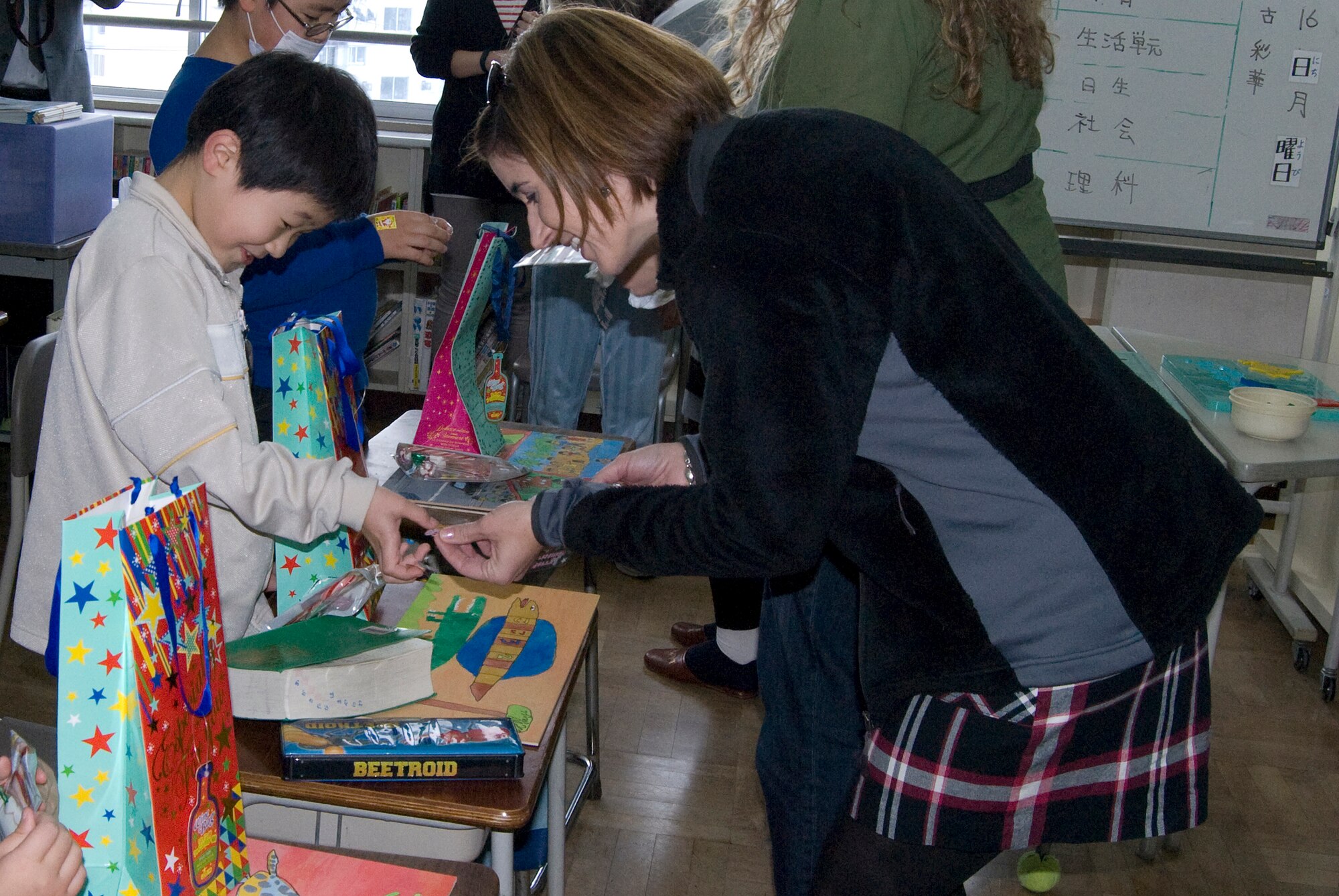 A spouse from Misawa Air Base gives a student from Kamikubo Shougaltuko
Elementary School a Christmas sticker during a recent visit in Misawa City, Japan, 
Dec. 16, 2013. A group of American and Japanese ladies along with Santa Claus went to the elementary school to surprise 18 Japanese students with gifts in an effort to expand relationships between the American and Japanese communities. (Courtesy 
Photo)
