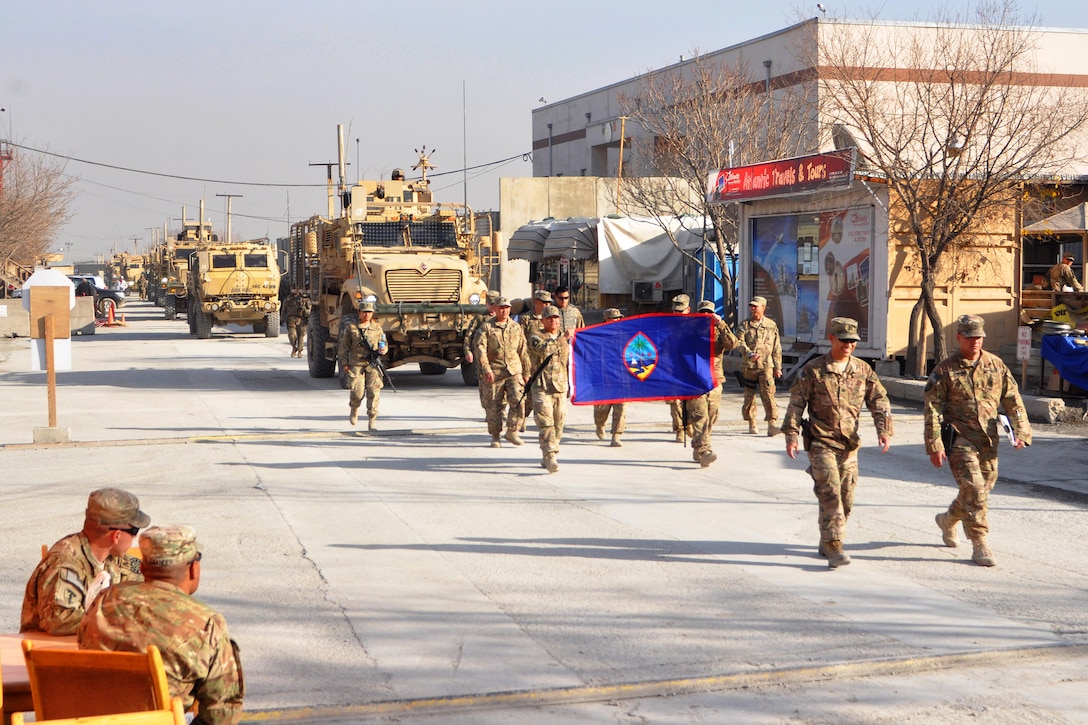 U.S. Army Capt. Gene Guerrero, left, and U.S. Army 1st Sgt. John T. Johnson, lead soldiers carring the Guam flag as they ground guide a convoy off from Camp Phoenix, Kabul, Afghanistan, Dec. 17, 2013. Guerrero, Johnson and the soldiers are assigned to Guam Army National Guard's Headquarters Company, 1st Battalion, 294th Infantry Regiment.