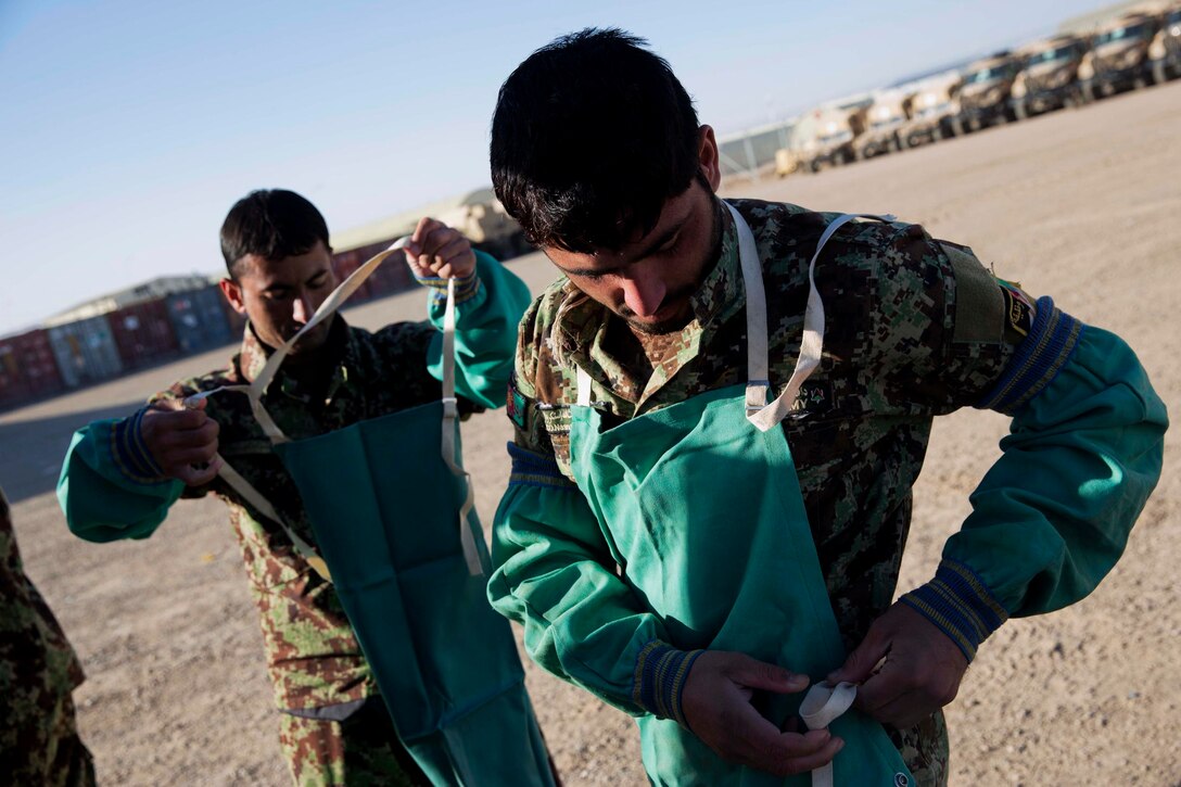 Afghan soldiers put on personal protective equipment during training on Camp Shorabak in Helmand province, Afghanistan, Dec. 17, 2013.