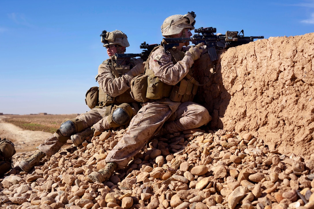U.S. Marine Corps Lance Cpls. Ian Forry, left, and Brian Schaeffer crouch behind a wall during a firefight with insurgents near a bazaar in the Nad Ali district of Afghanistan's Helmand province, Dec. 4, 2013. Forry and Schaeffer, riflemen, are assigned to the 1st Battalion, 9th Marines.
