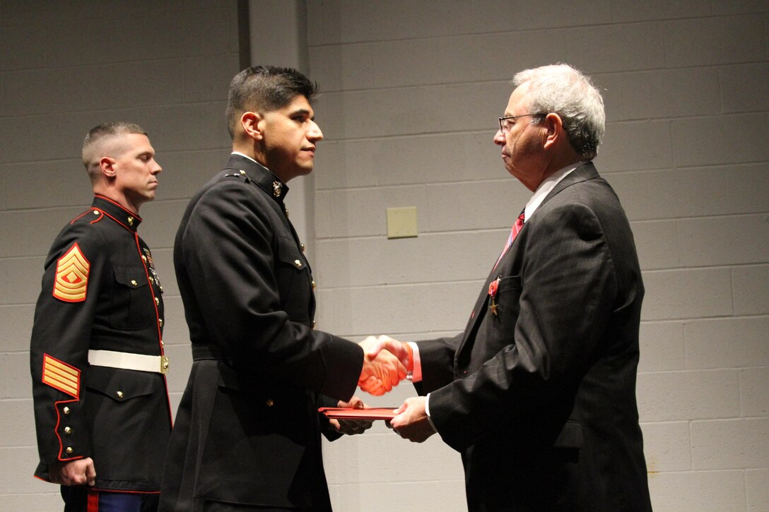 U.S. Marine Corps Capt. Daniel Campos, the company commander for Company L, 3rd Battalion, 25th Marine Regiment and U.S. Marine Corps 1st Sgt. Robert Waltz, the company first sergeant, award the Bronze Star Medal with Combat "V" device to Tim Padgett during a ceremony at the Marine Reserve Center in Columbus, Ohio Dec. 13, 2013. Padgett, a Vietnam War-era Marine, earned the award for actions during combat. (U.S. Marine Corps photo by Sgt. Tyler J. Hlavac/Released)