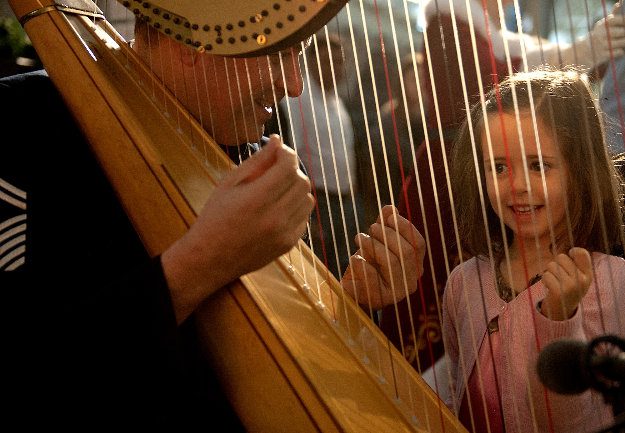 Senior Master Sgt. Eric Sabatino (left) explains how to play the harp to 5-year-old Sofia Hess after a holiday concert Dec. 15, 2013, at the Smithsonian National Air and Space Museum, Udvar-Hazy Center, Chantilly, Va.  Sabatino is an U.S. Air Force Band harpist. (U.S. Air Force photo/Staff Sgt. Carlin Leslie)