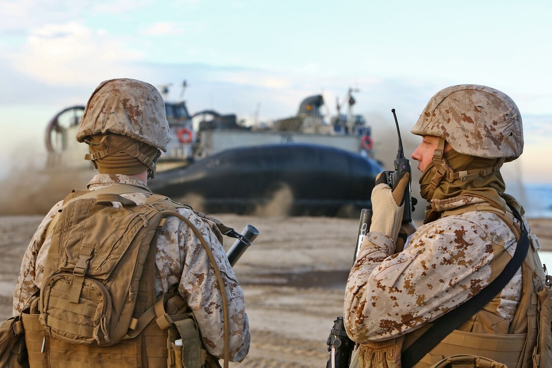 Private First Class John Schvab, left, and Pfc. Nicholas J. Trilk, both landing support specialists with Landing Support Company, Combat Logistics Regiment 17, 1st Marine Logistics Group, report a Landing Craft Air Cushion’s arrival on Red Beach during Exercise Steel Knight 2014 aboard Camp Pendleton, Calif., Dec. 11, 2013. The Marines supported ship-to-shore operations of 1st Light Armored Reconnaissance by coordinating the amphibious landing portion of the exercise. SK14 is a large-scale, combined arms, live-fire exercise that integrates aviation and logistical support from 3rd Marine Aircraft Wing and 1st MLG. Steel Knight tests 1st MLG’s capabilities of supporting a large scale operation.