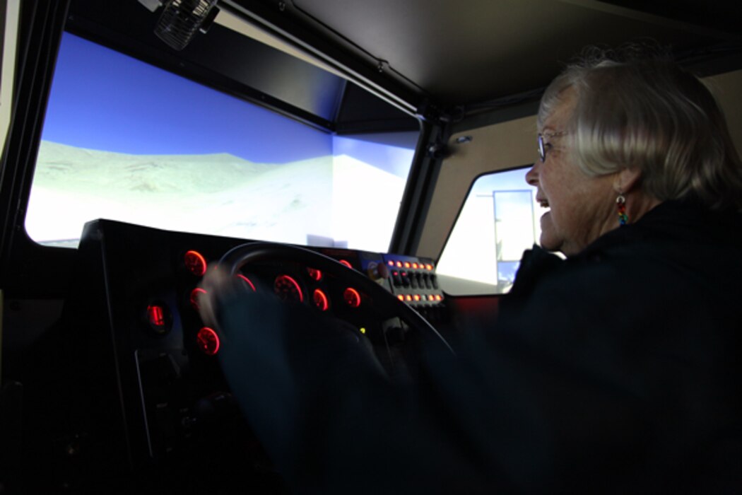 A tour participant gets a feel for being behind the while of a large tactical vehicle during a visit to the driving simulator at the Battle Simulation Center at Camp Wilson.