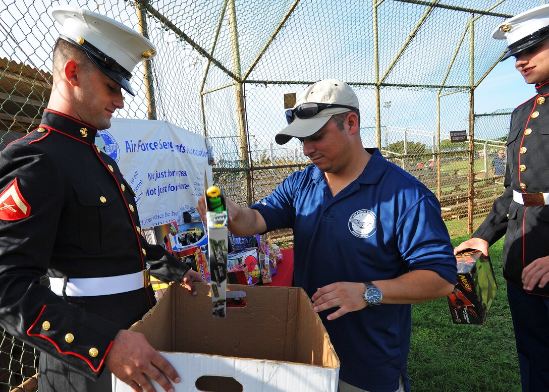 Senior Master Sgt. Guadalupe Ruiz, Pacific Air Forces/A4 manager, center, helps collect donated toys with “Toys for Tots” representatives, U.S. Marines Corps Lance Cpl. Doug Larrabee, left, and Lance Cpl. Brady Gilley, right, from the Heavy Marine Helicopter (HMH) 463, during the opening ceremonies for the 2nd Annual Super Draft Softball Tournament at Joint Base Pearl Harbor-Hickam, Hawaii, Dec. 14, 2013. The event was hosted by the AFSA and collected more than 70 toys for donations to “Toys for Tots.” (U.S. Air Force photo/Master Sgt. Jerome S. Tayborn)