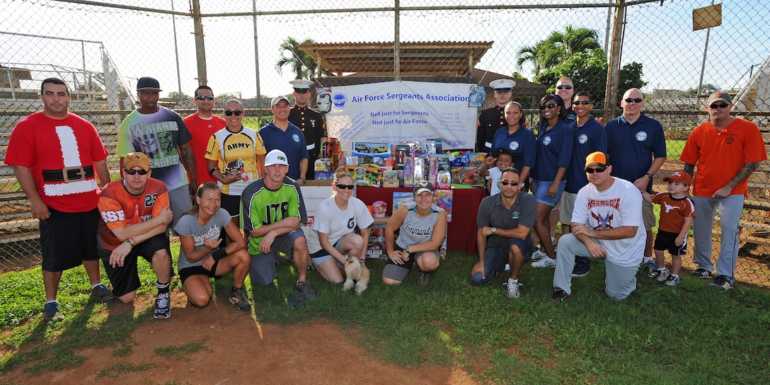 Volunteers and Joint Base Pearl Harbor-Hickam Air Force Sergeants Association members pose with U.S. Marines Corps “Toys for Tots” representatives for a group photo during the opening ceremonies of the 2nd Annual Super Draft Softball Tournament at the JBPHH, Hawaii, Dec. 14, 2013.  The event was hosted by the AFSA and collected more than 70 toys for donations to “Toys for Tots.” (U.S. Air Force photo/Master Sgt. Jerome S. Tayborn)