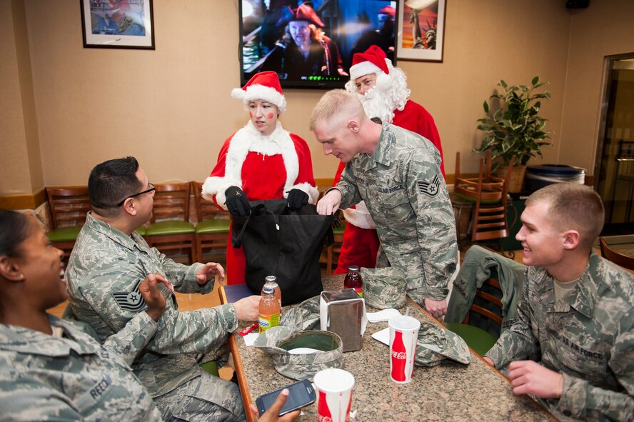 Members of the 8th Fighter Wing chapel give candy to Airmen of the Wolf Pack Dec. 18, 2013, at Kunsan Air Base, Republic of Korea. Members of the chapel traveled the base dressed as Santa and his helpers to spread holiday cheer. (U.S. Air Force photo by Senior Airman Clayton Lenhardt/Released)