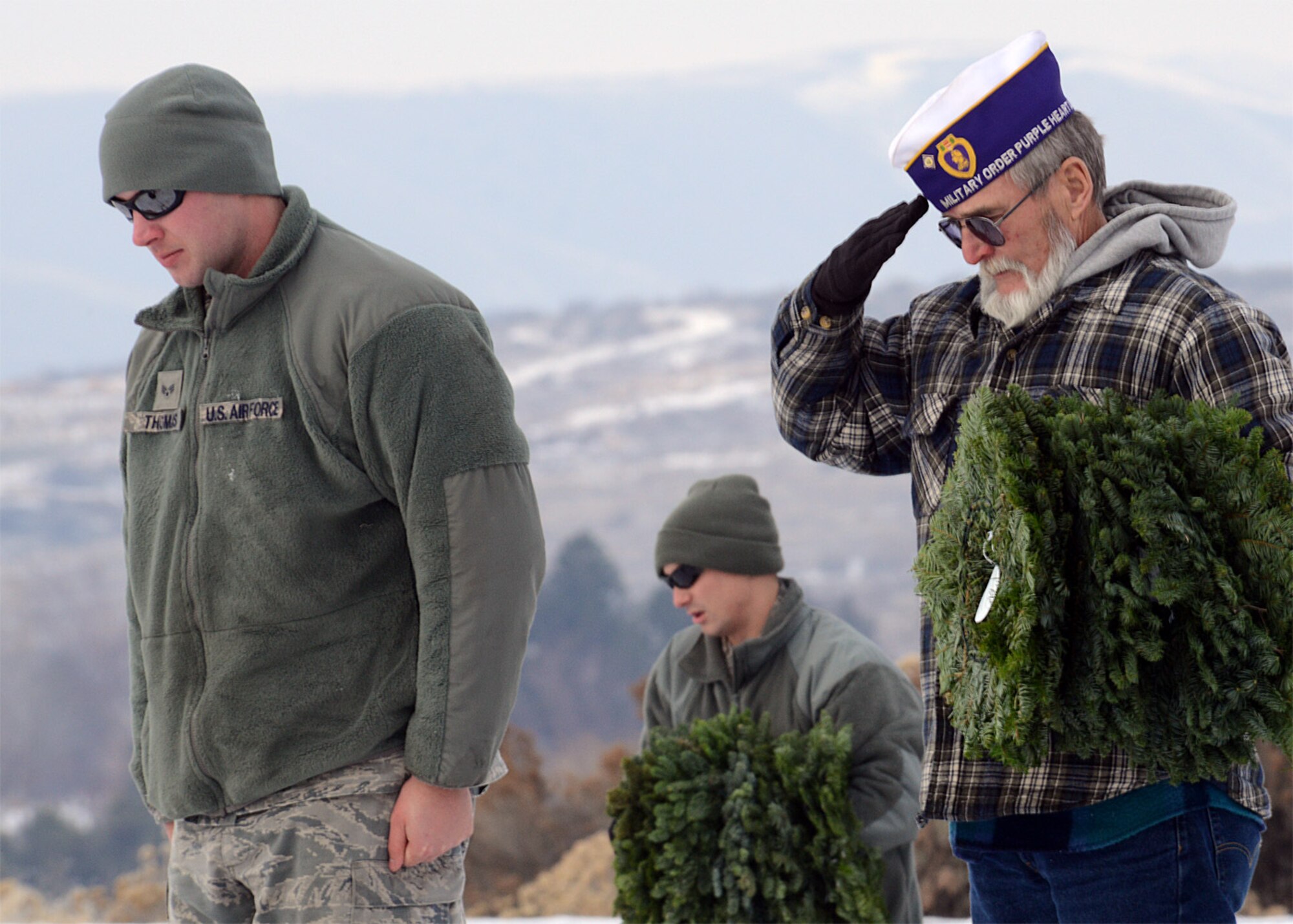 Air Force Senior Airman Jordan Thomas, 366th Logistics Readiness Squadron vehicle operator, Staff Sgt. Darren Albrecht, 366th LRS, and military veteran honor fallen service members during the Wreath Across America ceremony in Boise, Idaho, Dec. 13. 366th LRS squadron members and other Airmen from the base assisted Civil Air Patrol by placing a wreath on each grave to remind others that veterans will never be forgotten. (U.S. Air Force photo by Tech. Sgt. JT May III/RELEASED)

