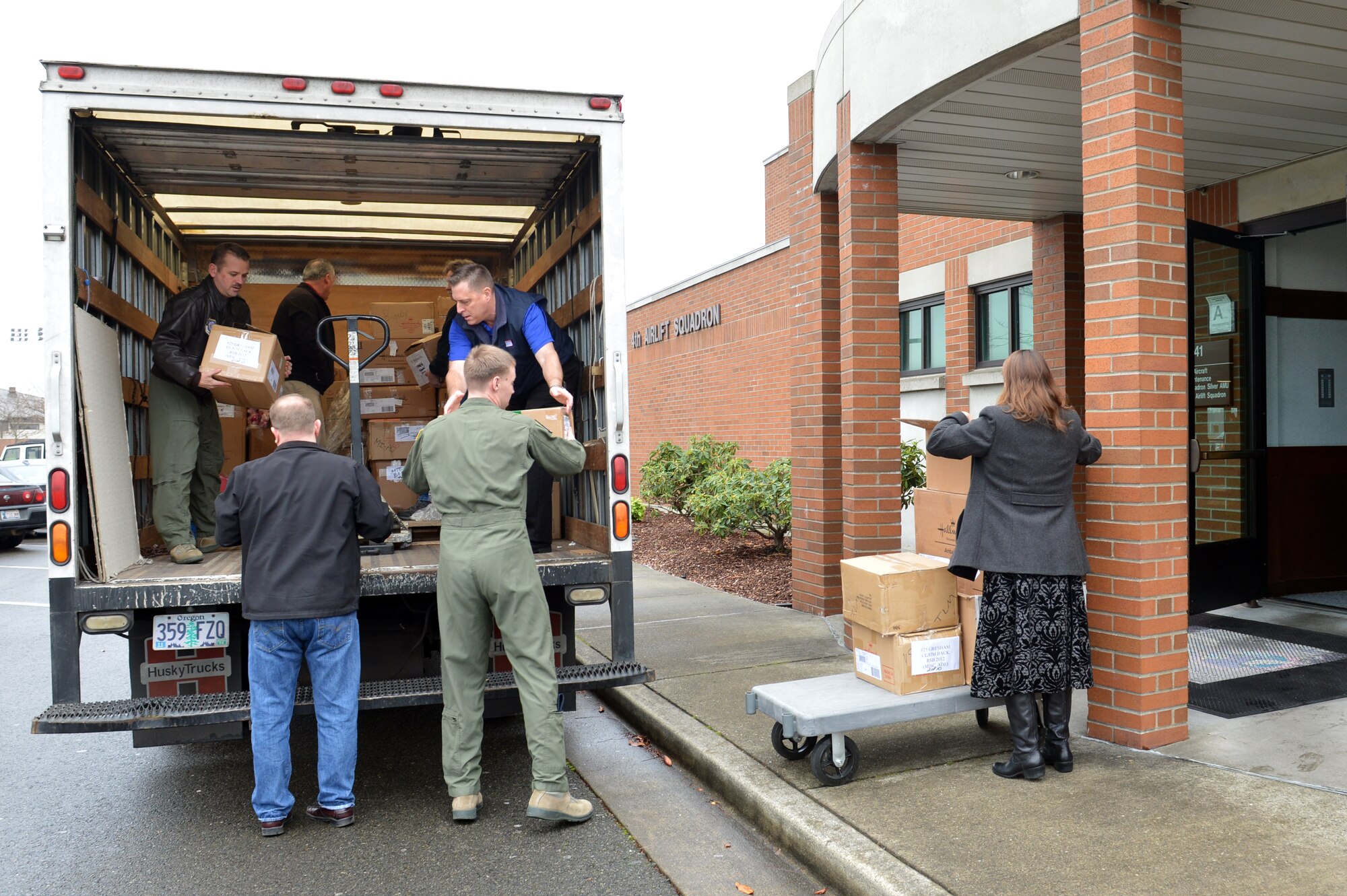 Lt. Col Matt Anderson, 4th Airlift Squadron commander, hands a box of donated electronic books to Senior Airman Trevor Melton, 4 AS loadmaster, as they unload 1,800 items from the back of a delivery truck Dec. 16, 2013, at Joint Base Lewis-McChord, Wash. Anderson will disperse the donated items out to McChord Field units prior to future deployments. (U.S. Air Force photo/Staff Sgt. Jason Truskowski)
