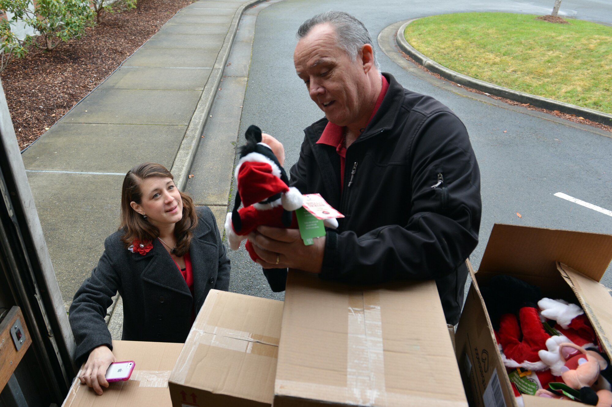 Jim Cox, Mark’s Hallmark president, and Christine Anderson, 4th Airlift Squadron Spouses Club president, smile as a donated electronic stuffed animal plays music and dances Dec. 16, 2013, at Joint Base Lewis-McChord, Wash. The donated items will be flown to deployed locations for military members to personalize, before the toys are sent to their own families back at Joint Base Lewis-McChord. (U.S. Air Force photo/Staff Sgt. Jason Truskowski)