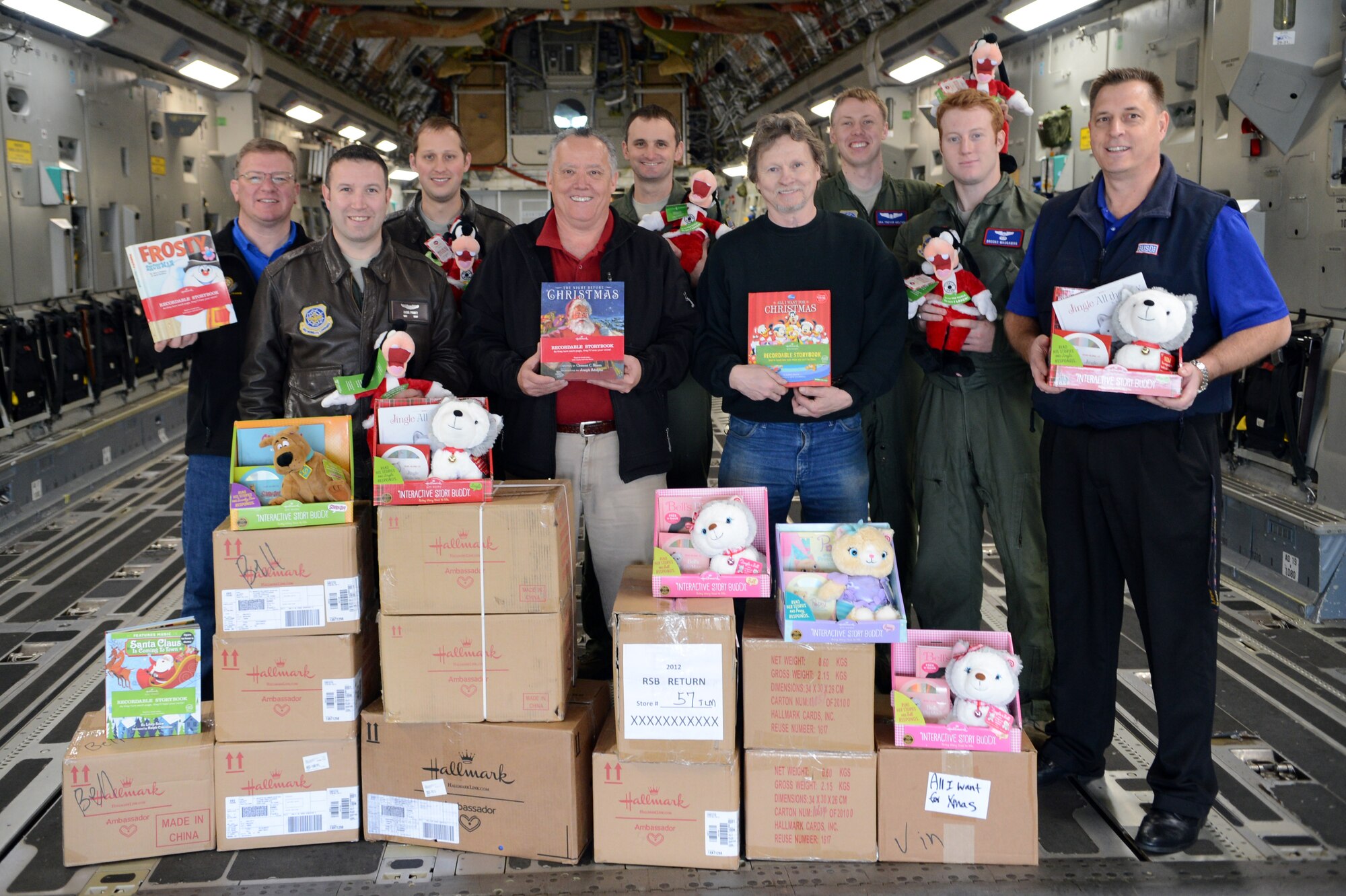 Military members and USO Northwest managers stand next to books and stuffed animals aboard a C-17 Globemaster III aircraft, Dec. 16, 2013, at Joint base Lewis-McChord, Wash. Community partners donated 1,800 recordable Christmas books and stuffed animals to deployed Air Force members and their families. (U.S. Air Force photo/Airman 1st Class Jacob Jimenez)
