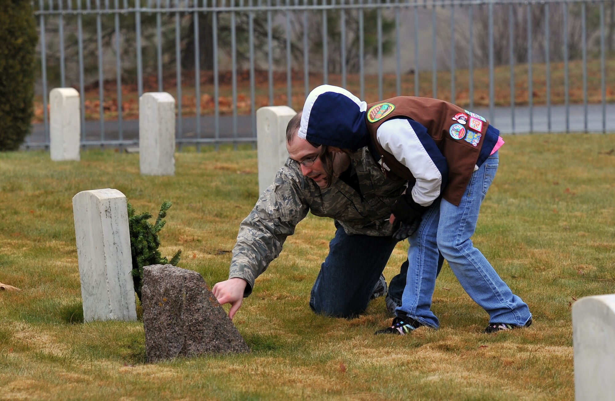 Tech. Sgt. Jason Weaver, 92nd Security Forces Squadron, and his daughter Phoebe, lay a wreath on a grave during Wreaths Across America at the Fort Wright Cemetery in Spokane, Wash., Dec. 14, 2013. The event is designed to spread the message about the importance of remembering fallen heroes, honoring those who served, and teaching children about the sacrifices made by veterans and their families to preserve freedom. (U.S. Air Force photo by Staff Sgt. Veronica Montes/Released)