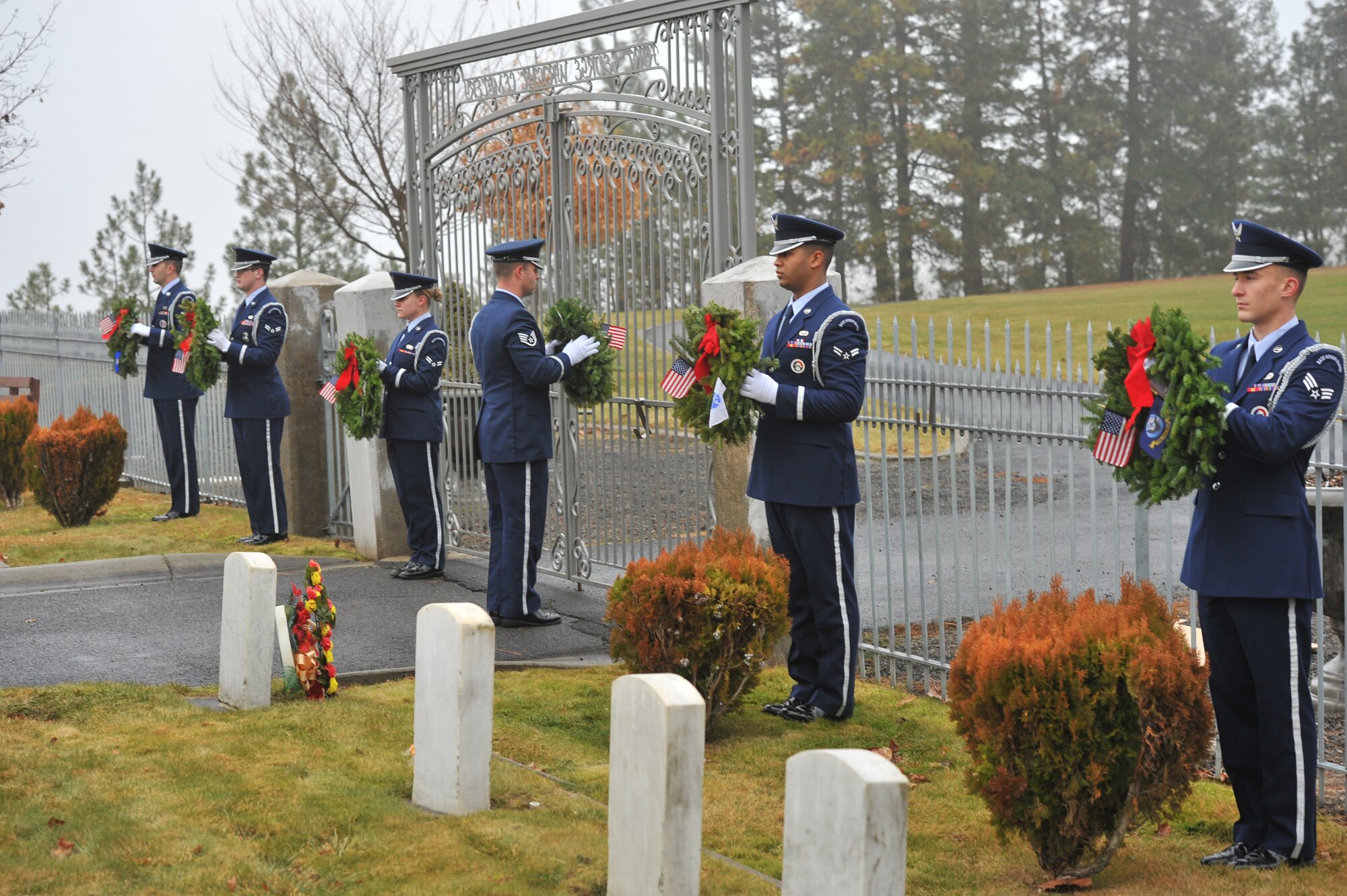 Members from the Fairchild Air Force Base honor guard lay wreaths representing the National flag, the Prisoners of War flag, and flags for all five military branches, during Wreaths Across America at the Fort Wright Cemetery in Spokane, Wash., Dec. 14, 2013. The event is designed to spread the message about the importance of remembering fallen heroes, honoring those who served, and teaching children about the sacrifices made by veterans and their families to preserve freedom. (U.S. Air Force photo by Staff Sgt. Veronica Montes/Released)