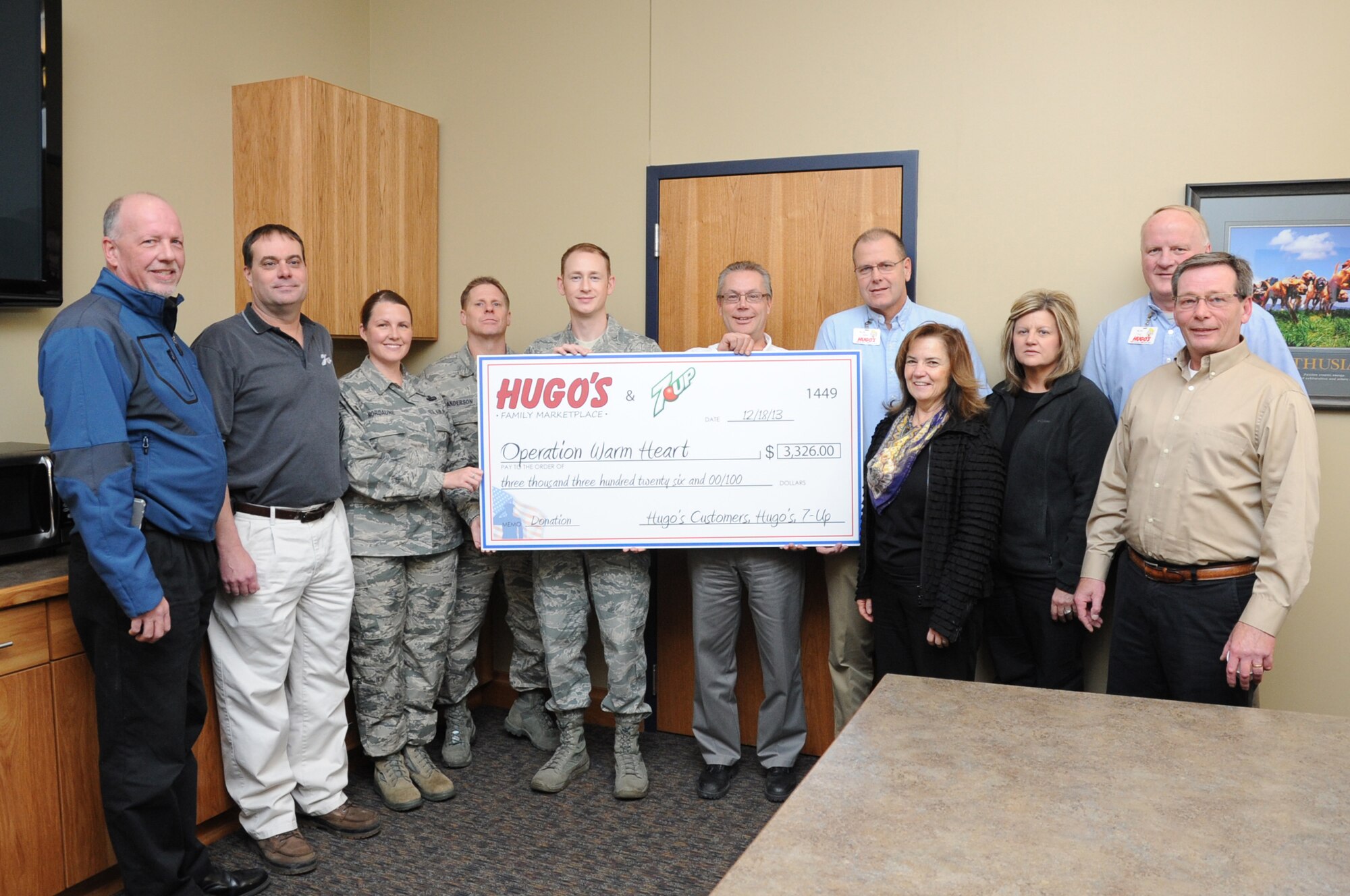 Representatives of Hugo's supermarkets present a check for $3,326 to members of the Grand Forks Air Force Base First Sergeants' Council Dec. 18, 2013, in Grand Forks, N.D. The money is to be used for Operation Warmheart, a program that provides emergency holiday funds to junior enlisted Airmen. (U.S. Air Force photo/Staff Sgt. David Dobrydney)