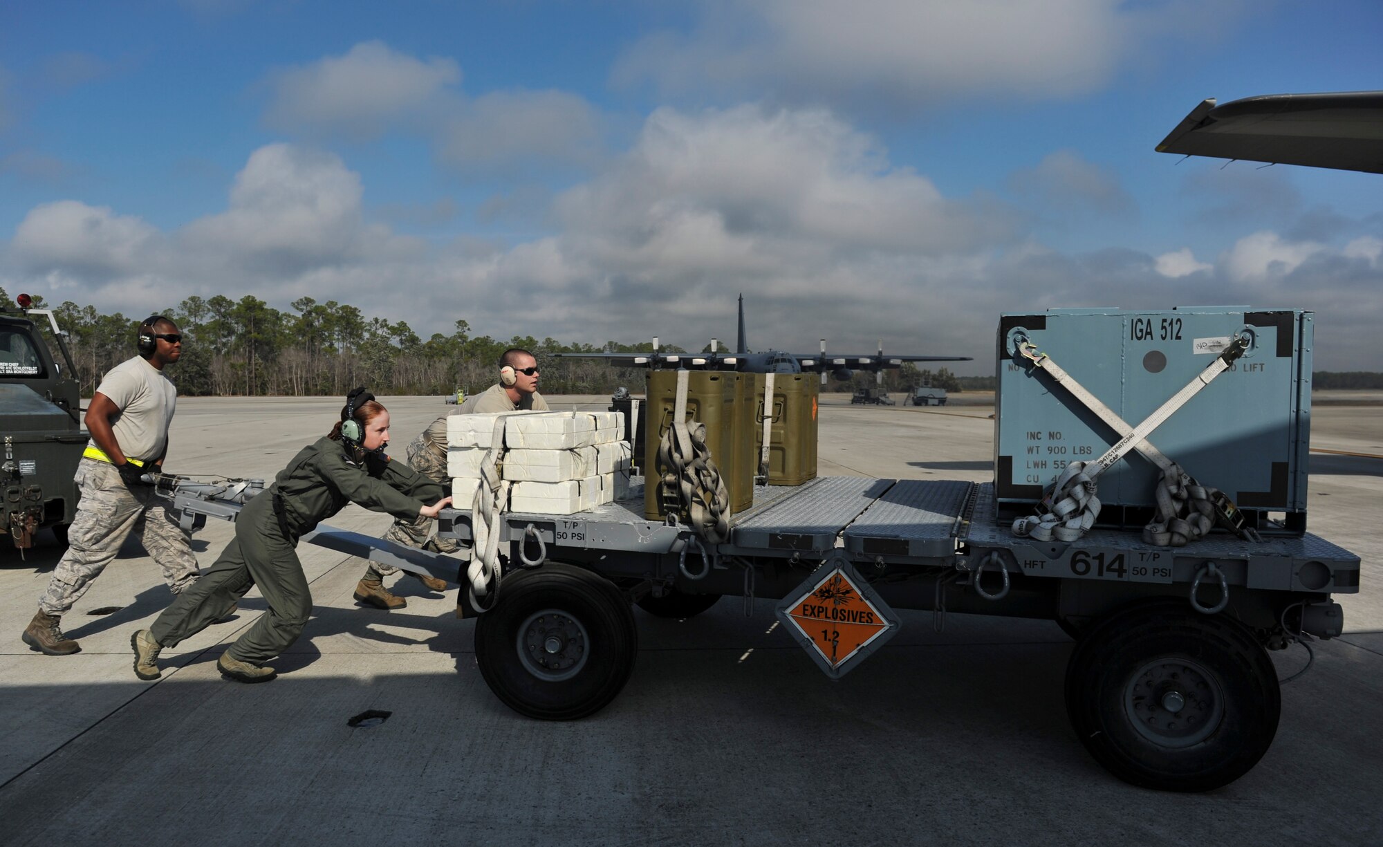 Senior Airmen Patrick Beam and Marcus Montgomery, 1st Special Operations Equipment Maintenance Squadron munitions line delivery drivers, push a munitions trailer with an aircrew member on Hurlburt Field, Fla., Dec. 6, 2013. Line delivery drivers handed 105mm rounds to aircrew members individually through a side door on the aircraft. (U.S. Air Force photo/Staff Sgt. John Bainter)