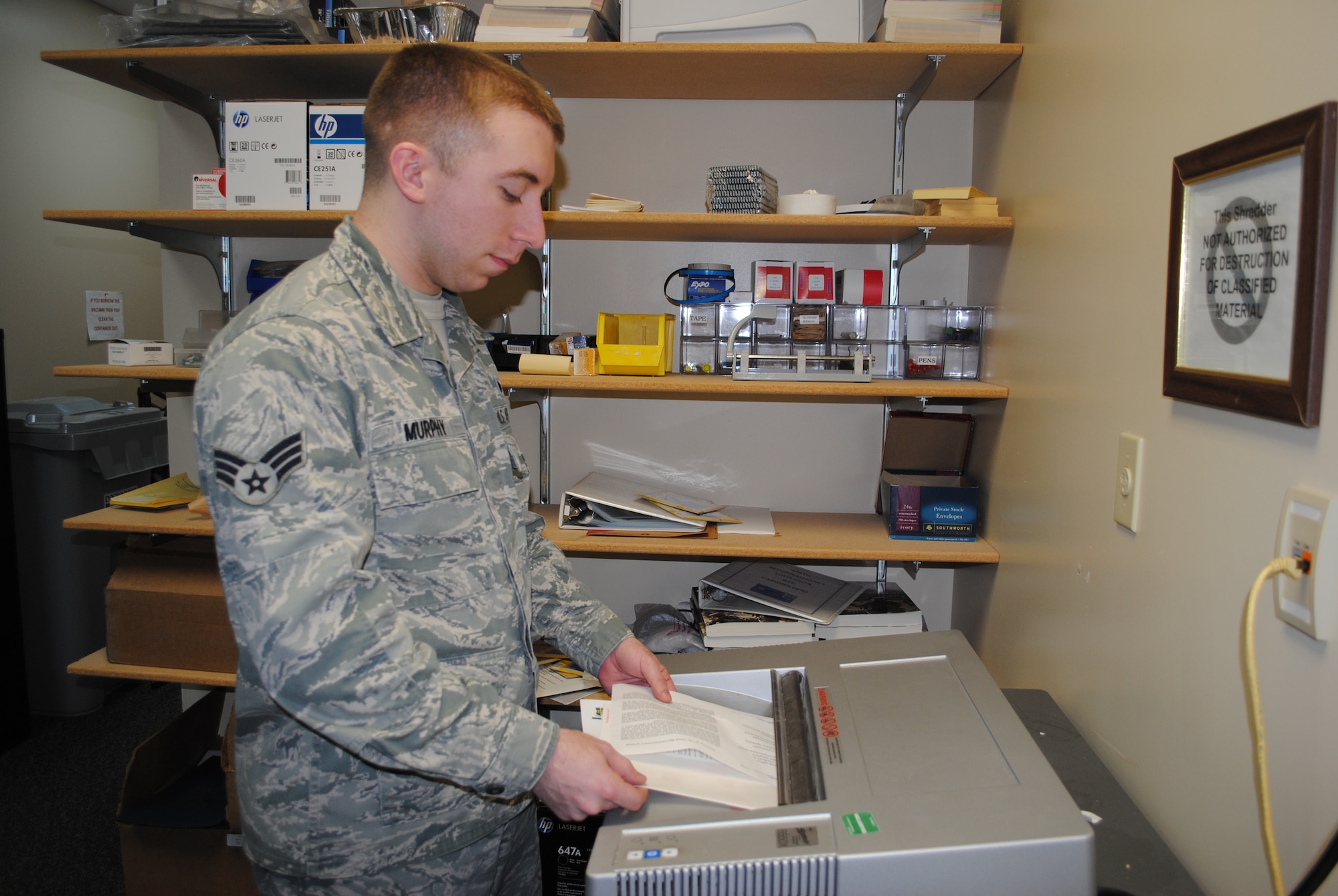 Senior Airman Michael Murphy of the 69th Reconnaissance Group shreds documents inside the 69th RG command section supply room Dec. 13, 2013, on Grand Forks Air Force Base, N.D. As a knowledge operations manager, Murphy oversees the records program for the 69th RG. (U.S. Air Force photo/Staff Sgt. Luis Loza Gutierrez
