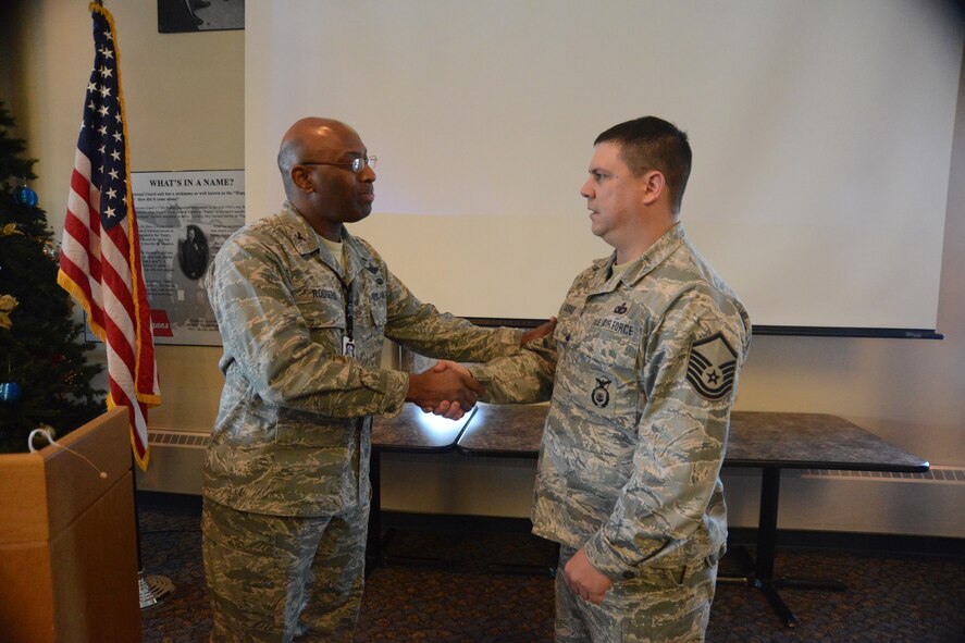 U.S. Air Force Col. Rickey Rodgers, the Air Combat Command inspector general team chief, left, presents a recognition coin to Master Sgt. James Casias, of the 119th Security Forces Squadron, at a compliance inspection out-brief at the North Dakota Air National Guard base, Fargo, N.D., Dec. 18, 2013. While many unit members were recognized as superior performers, the IG coin is given to very few people and Master Sgt. Casias is the only person to receive the coin at the out-brief. The briefing is the culmination of the compliance inspection, which the unit passed, with many areas receiving excellent and outstanding grades. 