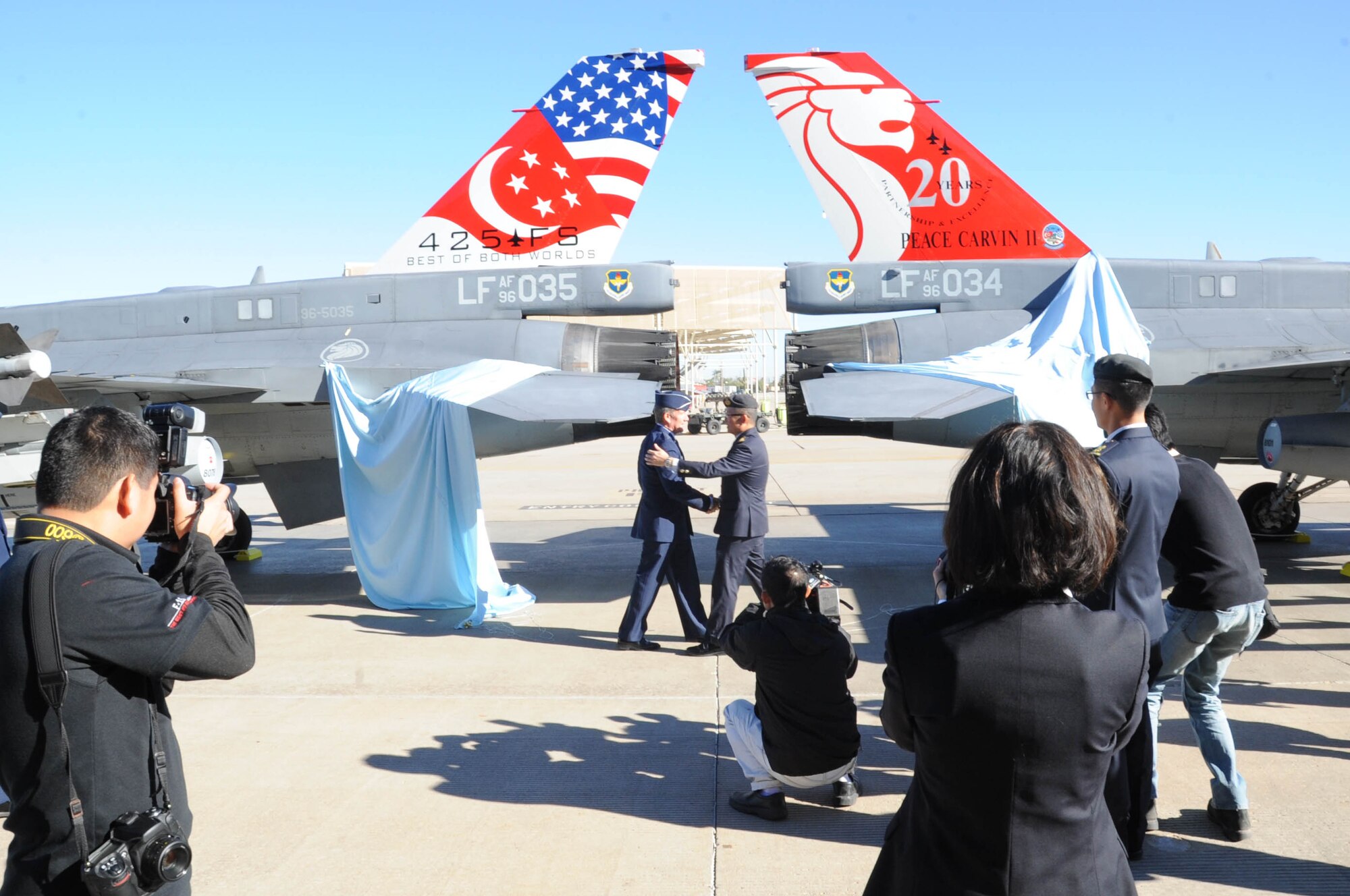 Gen. Hawk Carlisle (left), Pacific Air Forces commander, and Maj. Gen. Hoo Cher Mou, Republic of Singapore chief of air forces, shake hands after unveiling two newly-painted F-16 tail flashes following the Peace Carvin II Parade Dec. 11. The painted tail flashes commemorate the 20th anniversary of the RSAF partnering with Luke Air Force Base in training fighter pilots. (U.S. Air Force photo by Staff Sgt. Luther Mitchell Jr.)