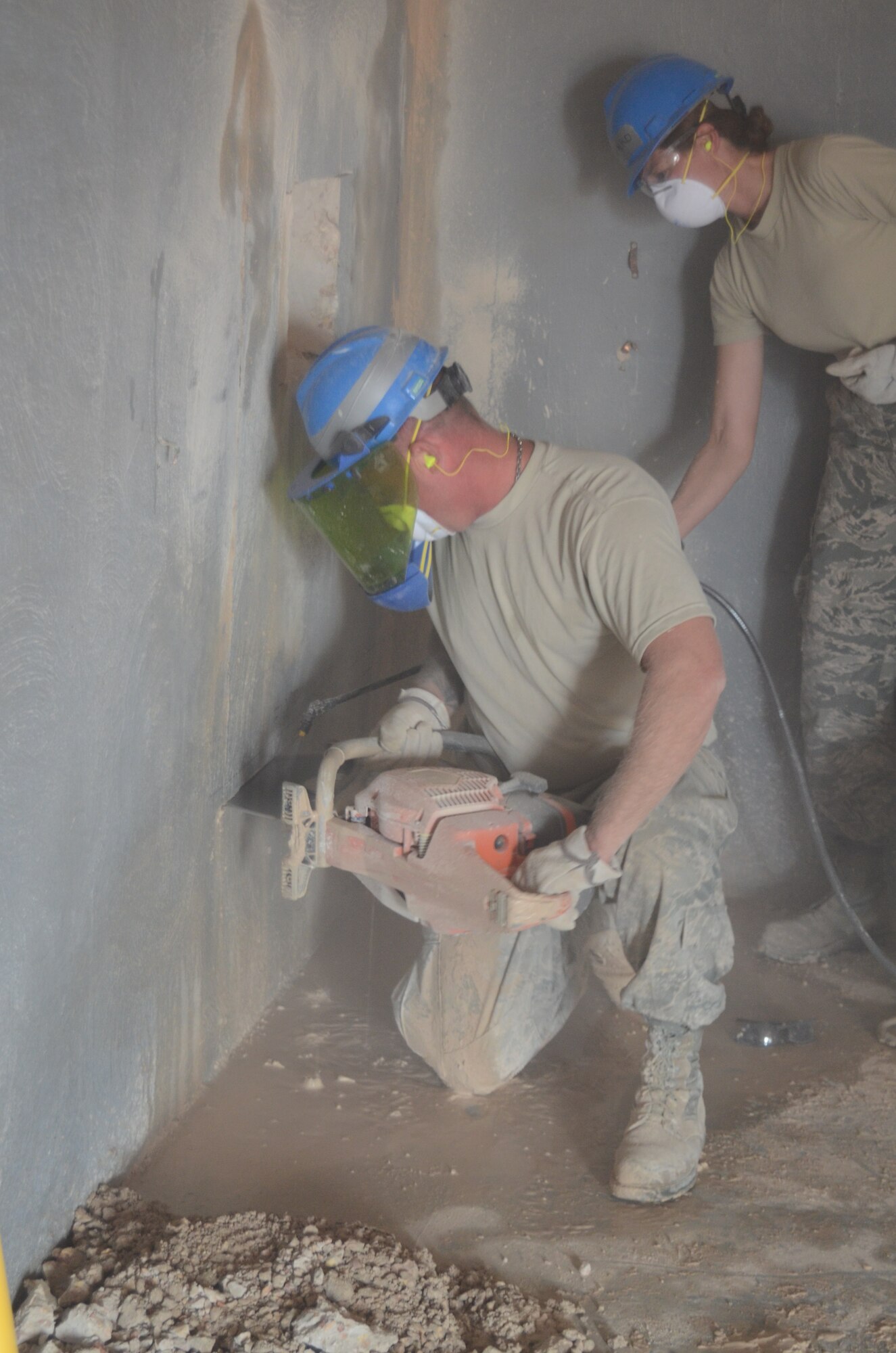 Master Sgt. Randy Frantz, a native of Troy Ill. and a member of 126th Civil Engineer Squadron attached to the 126th Air Refueling Wing, cuts a hole in a concrete wall to make a door way, while Capt. Allyson Benko, a native of Fairview Heights, also a member of the 126th Civil Engineer Squadron, sprays water on it to keep down the dust at Holt Naval Communication Station, Western Australia Aug. 28, 2013. The new door way is part of Operation C-Band Radar And Pedestal NCS NE Holt- Western Australia. (Air National Guard photo by Airman 1st Class Elise Stout)
