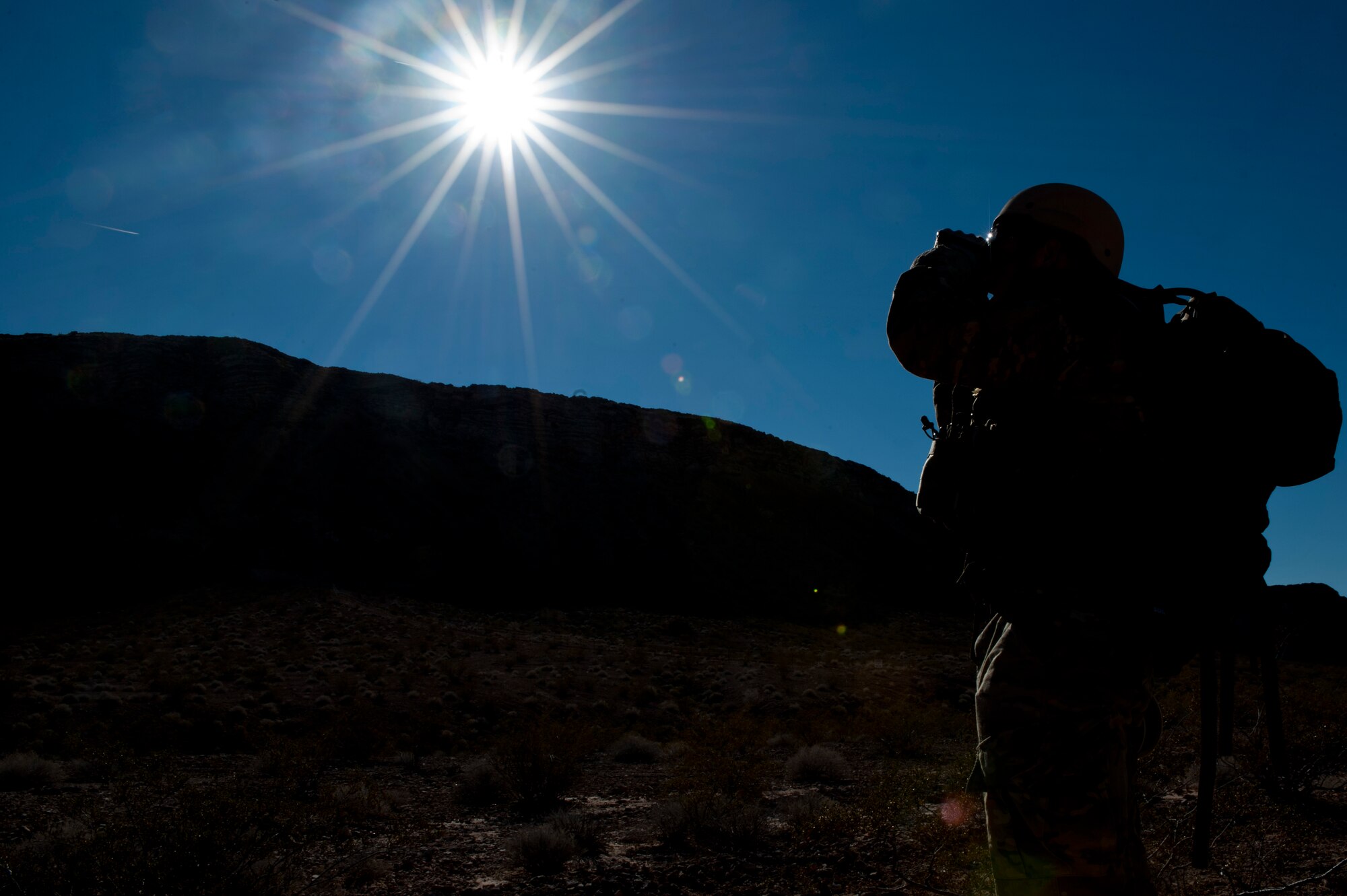 U.S. Air Force Staff Sgt. Daniel Esselstrom, 23rd Civil Engineering Squadron explosive ordnance disposal technician, Moody Air Force Base, Ga., looks through binoculars during an EOD counter-improvised explosive device training course Dec. 12, 2013, in Area 2 at Nellis AFB, Nev. The EOD counter-IED course provides advanced training for new EOD team leaders enabling them to hone their leadership management of counter-IED operations. (U.S. Air Force photo by Senior Airman Christopher Tam)