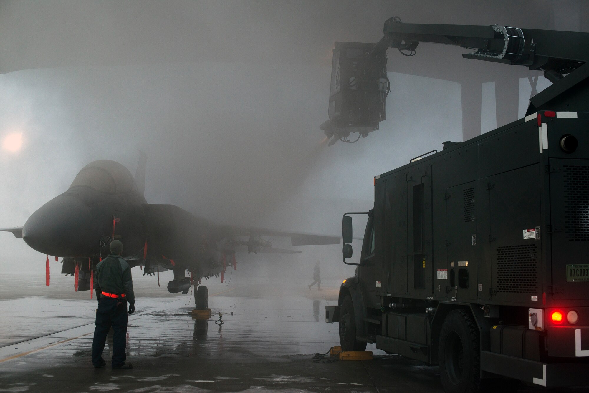 Air Force Senior Airman Brian Radtka, 366th Aircraft Maintenance Squadron crew chief, observes as Senior Airman Blake Pullen de-ices an F-15E Strike Eagle at Mountain Home Air Force Base, Idaho, Dec. 18, 2013.  Without crew chiefs and de-icing operations, the fleet could literally be grounded during frigid Idaho winter months. (U.S. Air Force photo by Master Sgt. Kevin Wallace/RELEASED)