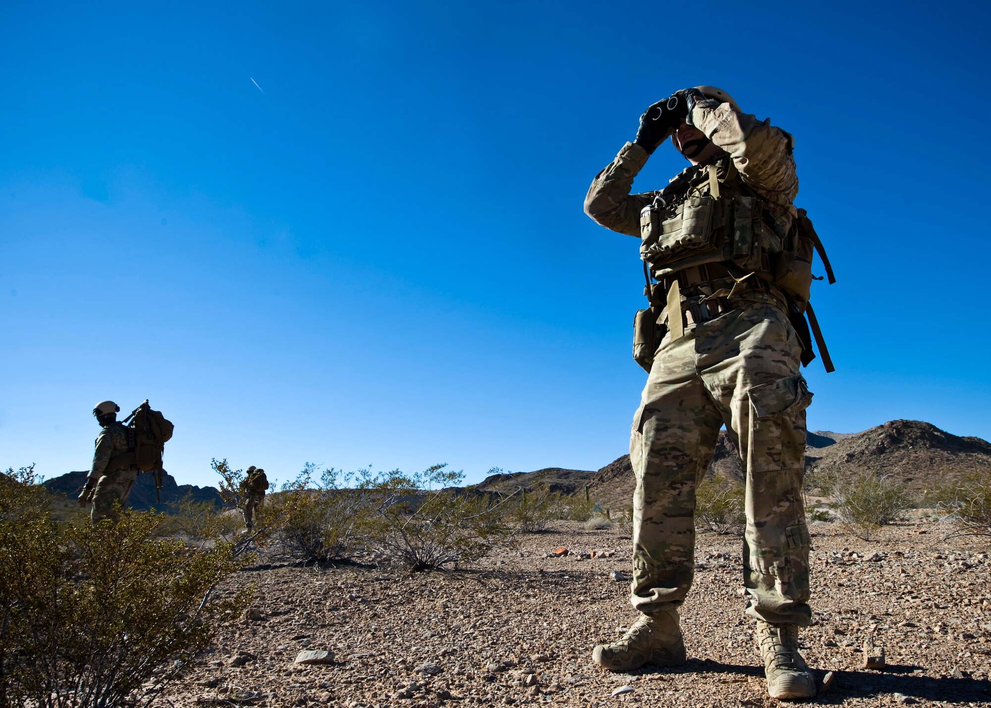 U.S. Air Force Staff Sgt. Daniel Esselstrom, 23rd Civil Engineer Squadron explosive ordnance disposal technician, Moody Air Force Base, Ga., utilizes binochulars during an improvised explosive device training course Dec. 12, 2013, in Area 2 at Nellis AFB, Nev. The course teaches students to understand the aspects of detecting and handling an improvised explosive device. (U.S. Air Force photo by Airman 1st Class Jason Couillard)