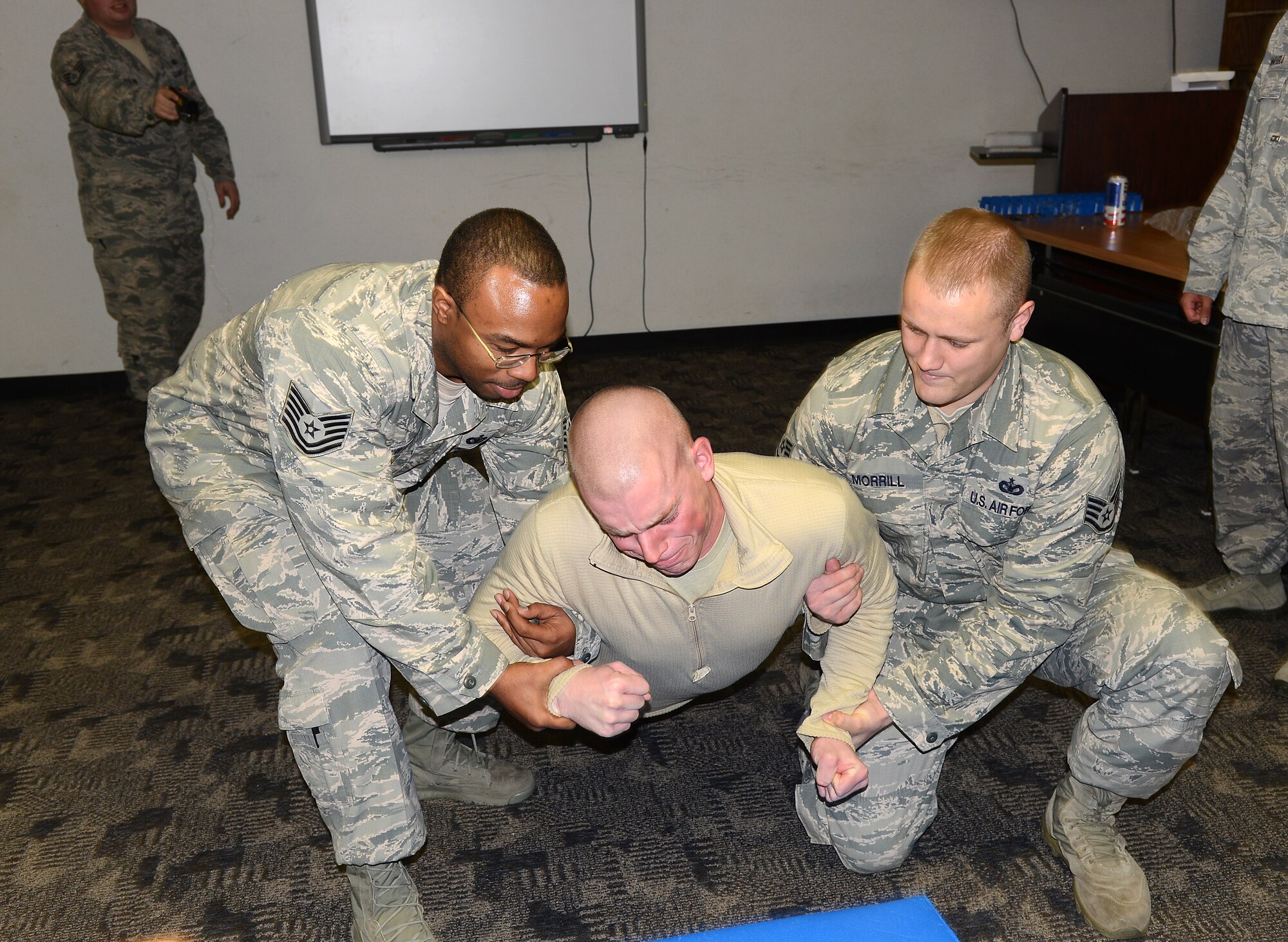 Staff Sgt. Jacob Seberger is voluntarily tased by Staff Sgt. Daniel Voliva during a 72nd Security Forces Squadron training class. For safety purposes, Tech. Sgt. Anthony Nixon, left, and Staff Sgt. Jason Morrill assist to ensure Sergeant Seberger falls to the floor safely. (Air Force photo by Kelly White)