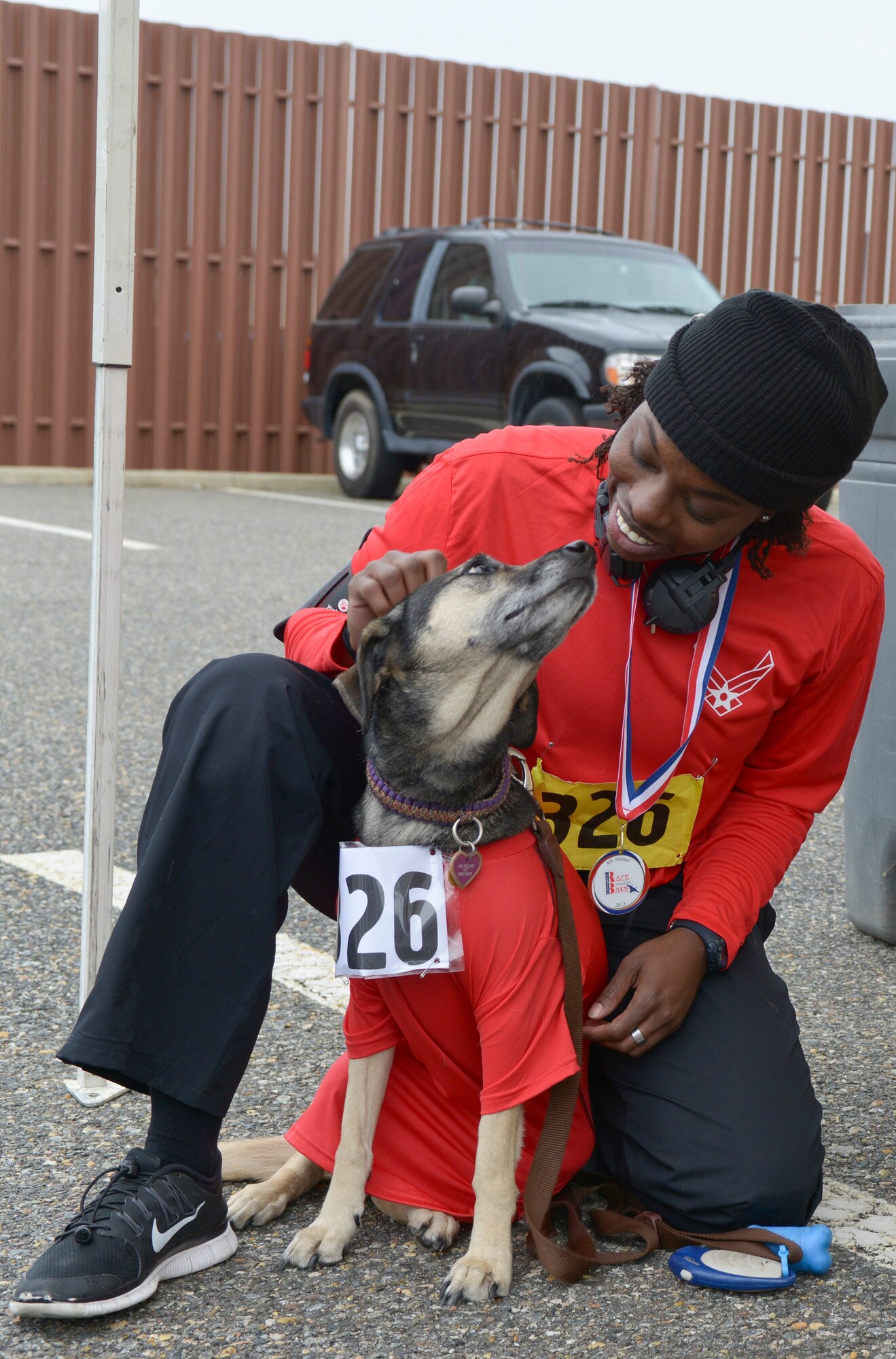 U.S. Air Force Master Sgt. Genese Williams, 439th Supply Operations Squadron bomber mission capability flight noncommissioned officer in charge, congratulates her dog Jada for completing the 4th annual “Race ‘Round the Base” at Langley Air Force Base, Va., Dec. 14, 2013.The pair were among the more than 100 participants to receive medals for completing the race. (U.S. Air Force photo by Senior Airman Connor Estes/Released)