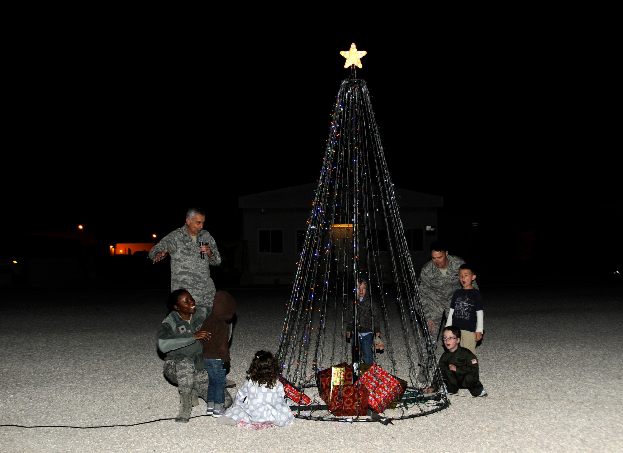 Brig. Gen. Roger H. Watkins invites children to light the Christmas tree at the 379th Air Expeditionary Wing in Southwest Asia, Dec. 16, 2013. Deployed service members and those with families here were invited to participate in the events held at Memorial Plaza. Watkins is the 379th AEW commander and hails from Fort Worth, Texas.  (U.S. Air Force photo/Senior Airman Hannah Landeros)