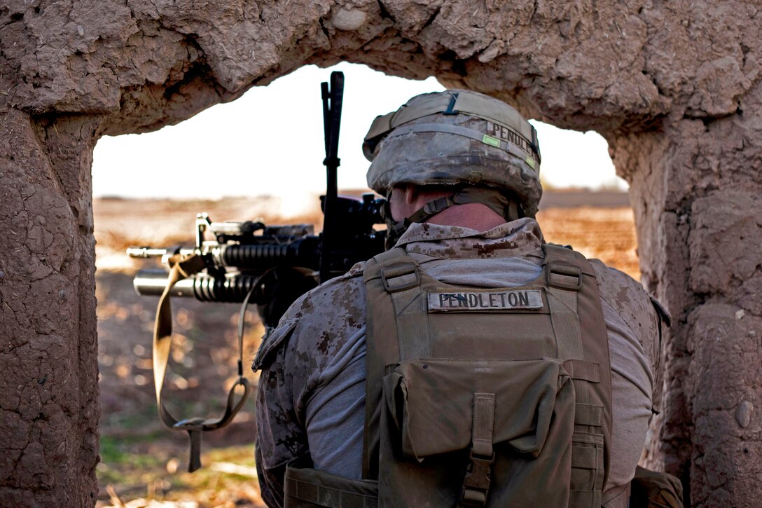 U.S. Marine Corps Sgt. Steven Pendleton searches for insurgents while standing in a doorway to a desert compound near a bazaar in the Nad Ali district of Helmand province, Afghanistan, Dec. 4, 2013. Pendleton, a squad leader, is assigned to 1st Battalion, 9th Marine Regiment.
