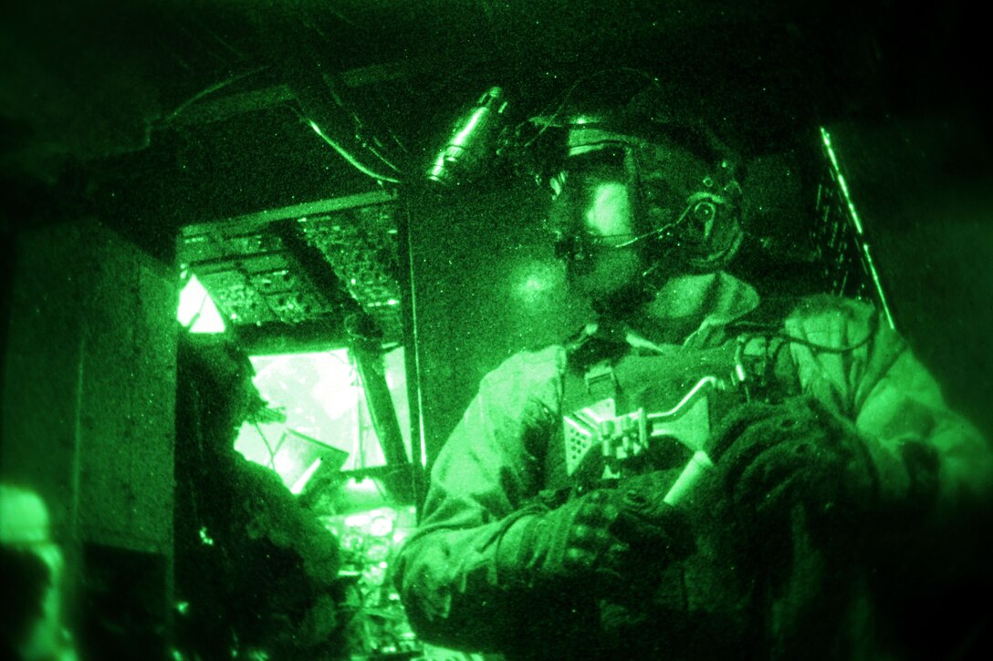 As seen through a night-vision device, U.S. Marine Corps Sgt. Ellis E. Russell prepares for takeoff from inside a U.S. Marine Corps CH-53E Super Stallion helicopter on Camp Bastion in Helmand province, Afghanistan, Dec. 17, 2013. Russell, a crew chief and assigned to Marine Heavy Helicopter Squadron 462, provided aerial support for British forces with Task Force Helmand during an operation.