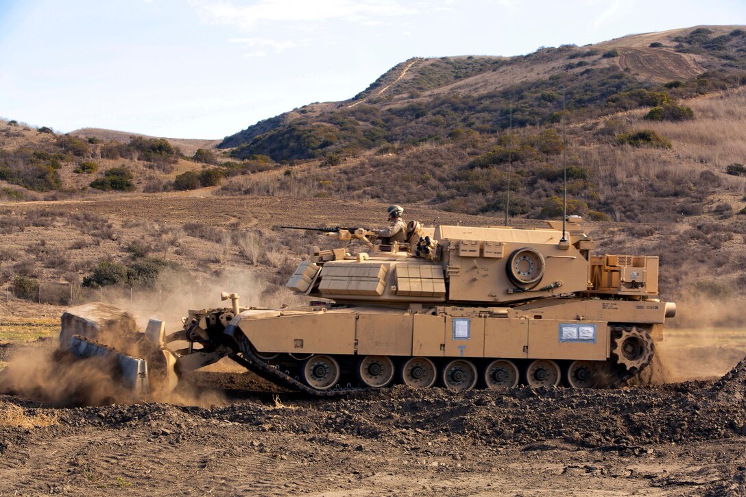 A Marine Corps assault breacher vehicle clears heavy debris from a path for an awaiting convoy while conducting complex obstacle-breaching exercises during Steel Knight 2014 on Camp Pendleton, Calif., Dec. 10, 2013.