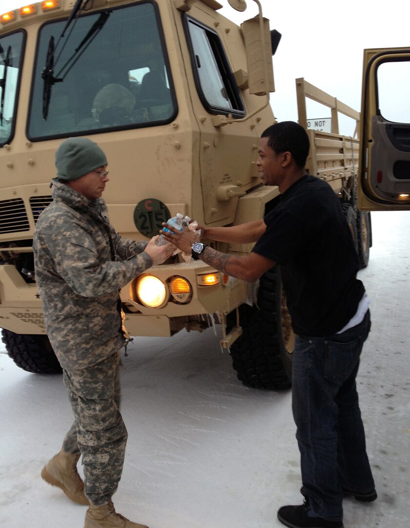 Spc. Douglas Rose, with the Texas Army National Guard's 236th Engineer Company, hands food and water to a long-haul truck driver near Sanger, Texas, after a winter storm stranded his rig Dec. 7, 2013. Soldiers from the Texas Army Guard were called out to provide assistance to state and local authorities during recent winter storms that hit the area. Soldiers were stationed along major highways in the area and helped stranded motorists.