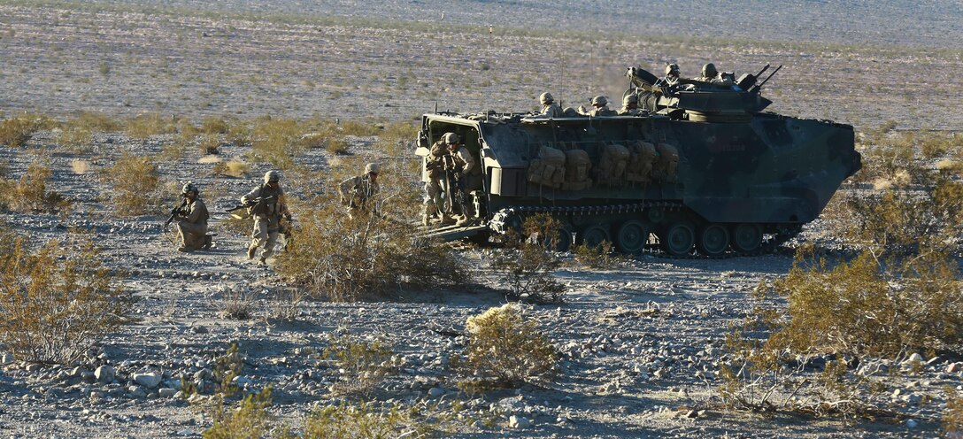 Marines with Alpha Company, 1st Battalion, 5th Marine Regiment, rush out the back of an assault amphibious vehicle and immediately start providing suppressing fire during a mechanized raid in support of Exercise Steel Knight 2014 at Marine Corps Air Ground Combat Center Twentynine Palms, Calif., Dec. 13, 2013. The battalion played a vital role in the ground combat element during the assault which prepared them for their upcoming deployment to Australia. Steel Knight is an annual exercise that includes elements from the entire I Marine Expeditionary Force (MEF). The exercise focuses on conventional operations and provides realistic training that prepares Marines for overseas operations. (U.S. Marine Corps photo by Cpl. James Gulliver/Released)