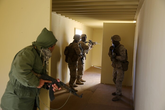 Marines with Bravo Company, 1st Battalion, 7th Marine Regiment, clear a building with Afghan role-players during a counterinsurgency exercise on Range 220 at Marine Corps Air Ground Combat Center Twentynine Palms, Calif., Dec. 9, 2013. The $140 million urban warfare training facility consists of more than 1,000 buildings and is divided into four sectors. The buildings replicate what can be found in an urban town to include gas stations, factories, one story complexes, marketplaces and multiple story buildings.