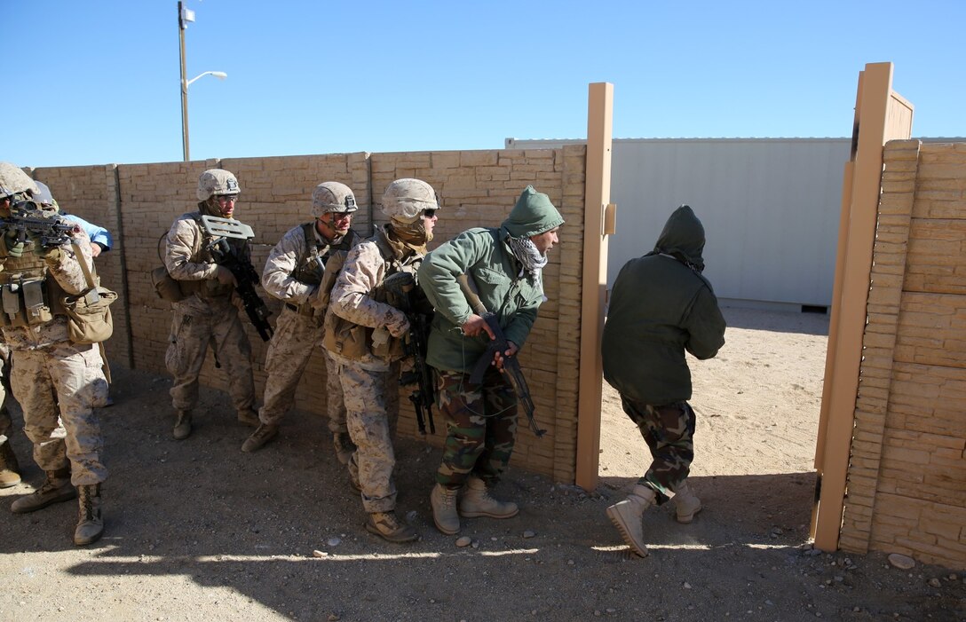 Marines with Bravo Company, 1st Battalion, 7th Marine Regiment, follow Afghan role-players into a compound during a counterinsurgency exercise on Range 220 at Marine Corps Air Ground Combat Center Twentynine Palms, Calif., Dec. 9, 2013. The $140 million urban warfare training facility consists of more than 1,000 buildings and is divided into four sectors. The buildings replicate what can be found in an urban town to include gas stations, factories, one story complexes, marketplaces and multiple story buildings.