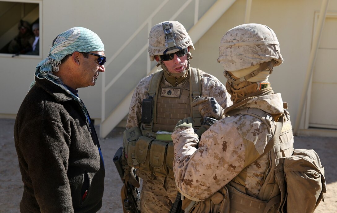 Staff Sgt. Matt Ingwerson, center, platoon sergeant, Bravo Company, 1st Battalion, 7th Marine Regiment, speaks with Lance Cpl. Kevin Zalewski, rifleman, to understand what a role-player is saying during a counterinsurgency exercise on Range 220 at Marine Corps Air Ground Combat Center Twentynine Palms, Calif., Dec. 9, 2013. Zalewski, a native of Chapel Hill, N.C., attended a Pashtu language course at San Diego State University to assist the battalion during their deployment. The $140 million urban warfare training facility consists of more than 1,000 buildings and is divided into four sectors. The buildings replicate what can be found in an urban town to include gas stations, factories, one story complexes, marketplaces and multiple story buildings.