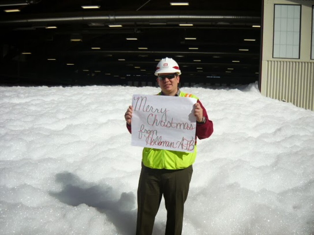 HOLLOMAN AIR FORCE BASE, N.M., -- 2013 Photo Drive submission. Photo by Daniel Garcia. "A Corps employee holds a sign that reads "Merry Christmas from Holloman AFB" outside a hangar where a foam dump test was performed."