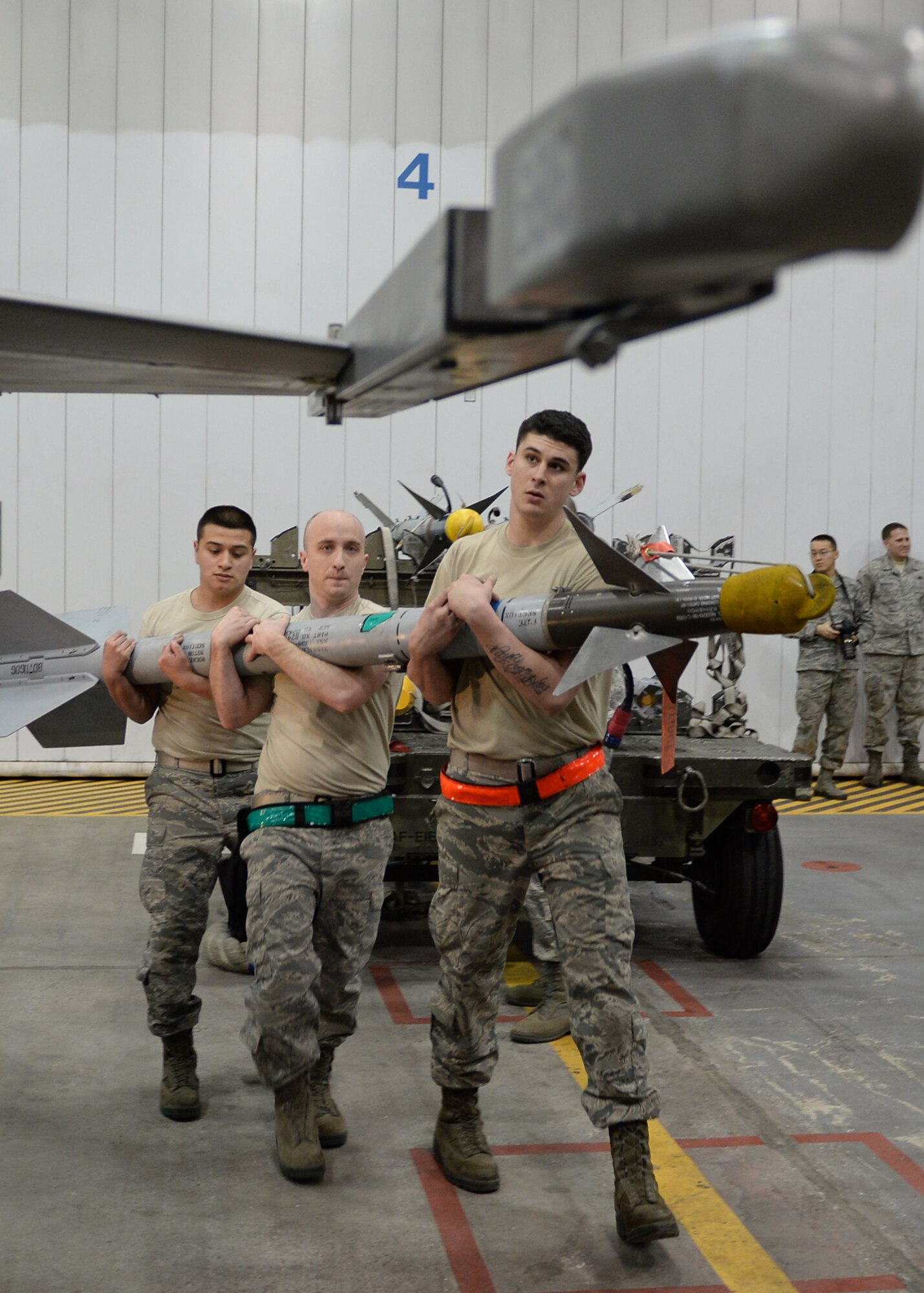 U.S. Air Force Airman 1st Class Uziel Huerta, Staff Sgt. Joe Craddock and Senior Airman Joseph Levin, 354th Aircraft Maintenance Squadron weapons load crew members, carry an AIM-9 Sidewinder Missile to the wing of an F-16 Fighting Falcon in an aircraft maintenance hangar during an annual load crew competition Dec. 13, 2013, Eielson Air Force Base, Alaska. Dallinger led his team, Crew 4, in a competition that highlighted Eielson's top performing load crews. (U.S. Air Force photo by Senior Airman Shawn Nickel/Released)
