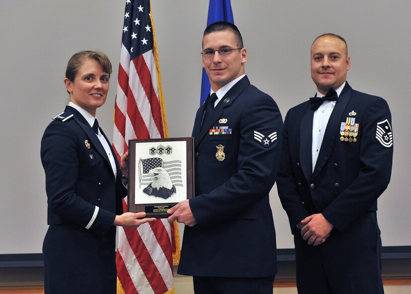 Senior Airman Travis Quimby, 341st Security Forces Squadron, center, receives a Distinguished Graduate award at the Airman Leadership School Class 14-B graduation banquet.  Shown presenting the award are Col. Marné Deranger, 341st Missile Wing vice commander, and Master Sgt. William Baccus, 341st Missile Security Forces Squadron first sergeant.  The Distinguished Graduate award recognizes superior performance in all areas of the course.  The graduation banquet was held Dec. 17 at the Grizzly Bend.  (U.S. Air Force photo / John Turner)