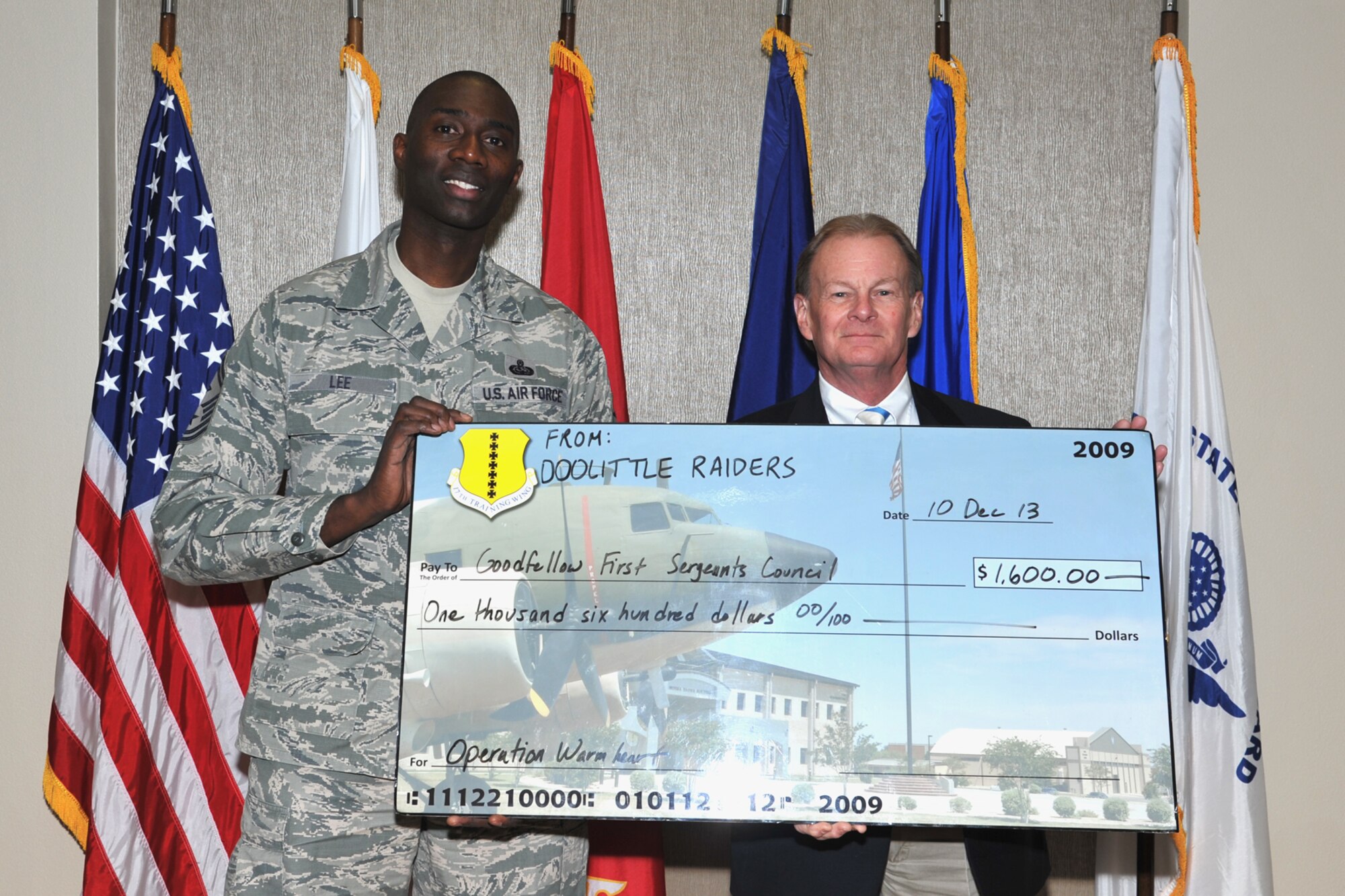 GOODFELLOW AIR FORCE BASE, Texas—Theodore Hargrove, 316th Training Squadron Honorary Commander, presents a check to Senior Master Sgt Hamp Lee, 316th Training Squadron first sergeant Dec. 10.Operation Warmheart is an Air Force First Sergeant program provided at Goodfellow throughout the year to help any base personnel in need. (U.S. Air Force photo/ Senior Airman Michael Smith)
