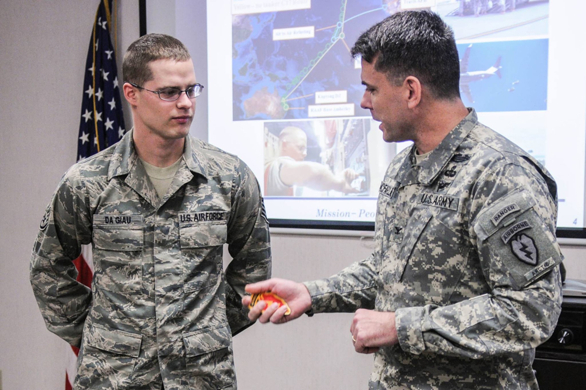 Army Col. Matthew McFarlane, commander of the 4th Brigade Combat Team (Airborne), 25th Infantry Division, presents Air Force SSgt. Todd DaGiau, an Air Transportation Specialist assigned to 732nd Mobility Squadron, a Spartan Brigade coin on Joint Base Elmendorf-Richardson, November 24, 2013. DaGiau, a ten-year Air Force veteran and native of Plains, Mont., was recognized for his timely actions during Talisman Saber. (Courtesy photo)