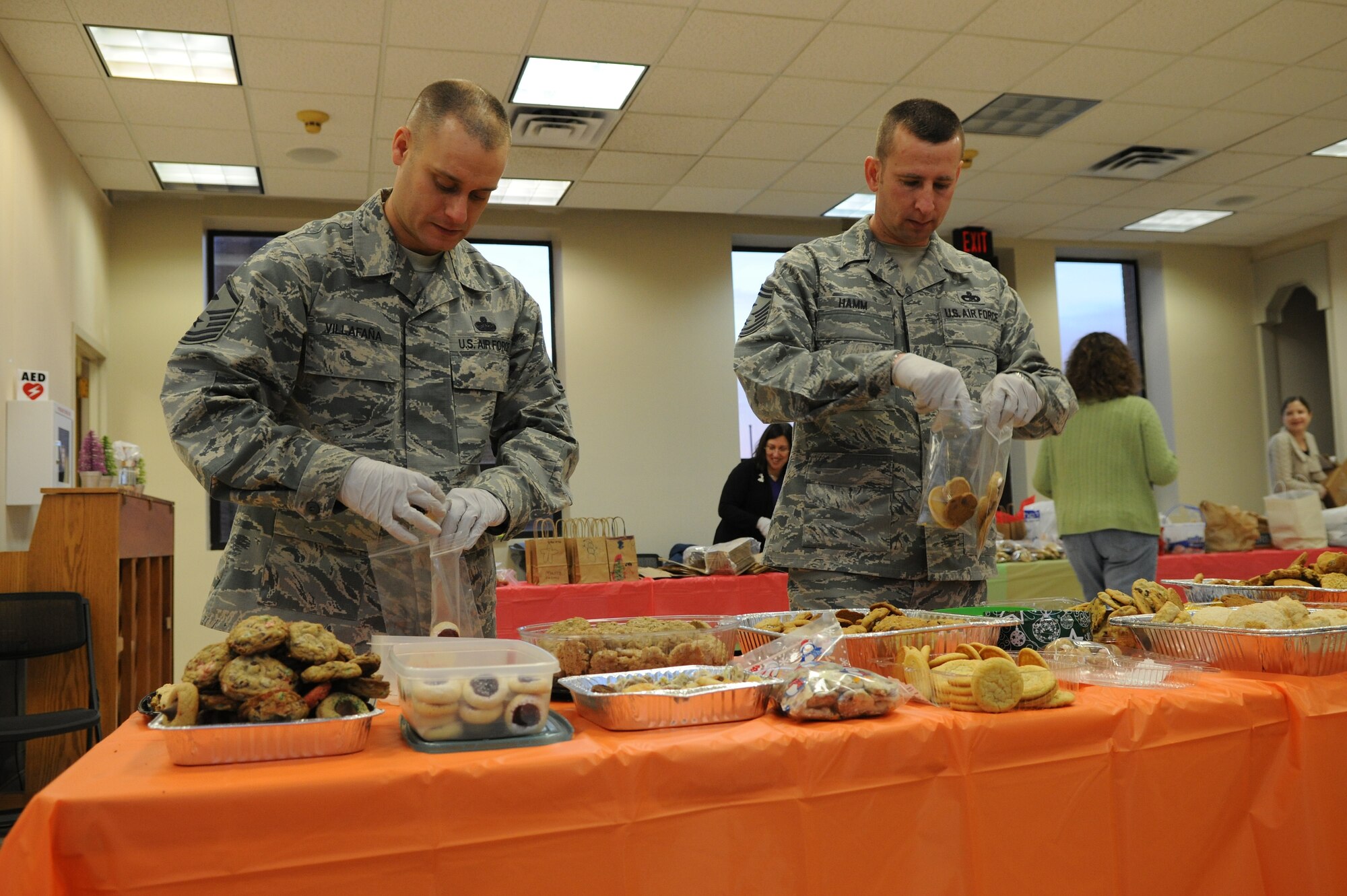Master Sgt. Eric Villafaña, 11th Comptroller Squadron’s first sergeant, and Senior Master Sgt. Johnny Hamm, Air Force District of Washington’s first sergeant, bag cookies for service members during the annual Cookie Caper Dec. 19. This year the event had approximately 550 dozen cookies that were baked, bagged and delivered.(U.S. Air Force photo/Airman 1st Class Ryan J. Sonnier)