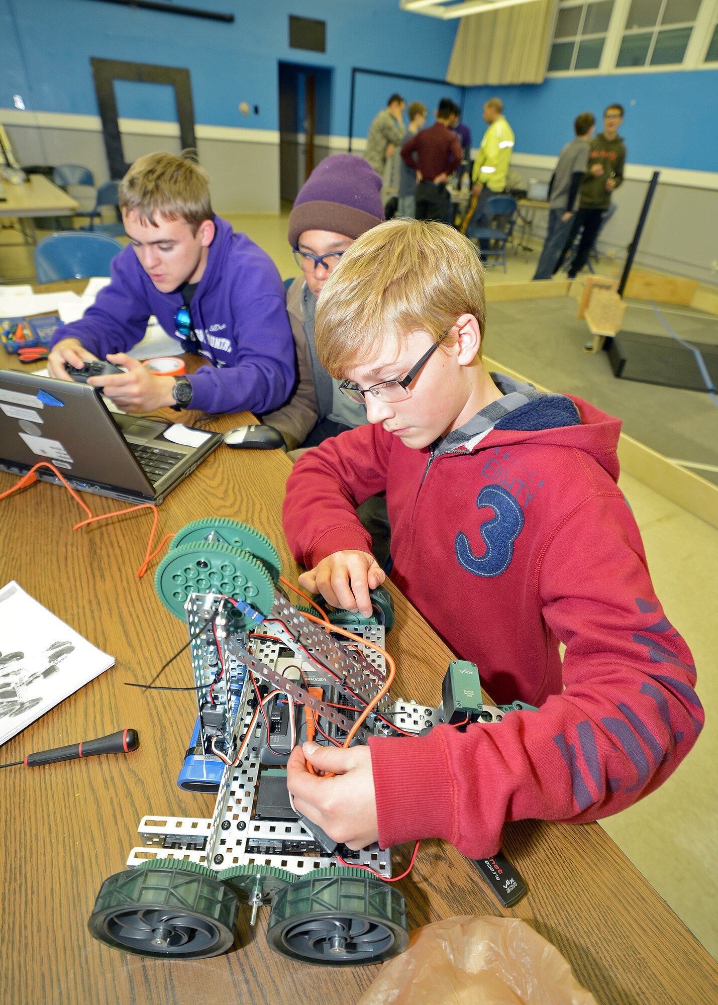 (From front to back) Samuel Munro, Clinton Boone and Larson LeDuc, Desert Jr. and Sr. High School students and members of the DHS Scorpions robotics team, work out the coding issues on one of their autonomous robots prior to the FIRST Tech Challenge robotics qualifying competition in Claremont, Calif., on Dec. 14. The team not only won their qualifying tournament but moved onto the regional competition which will be held in Los Angeles Feb. 22, 2014. (U.S. Air Force photo by Jet Fabara)